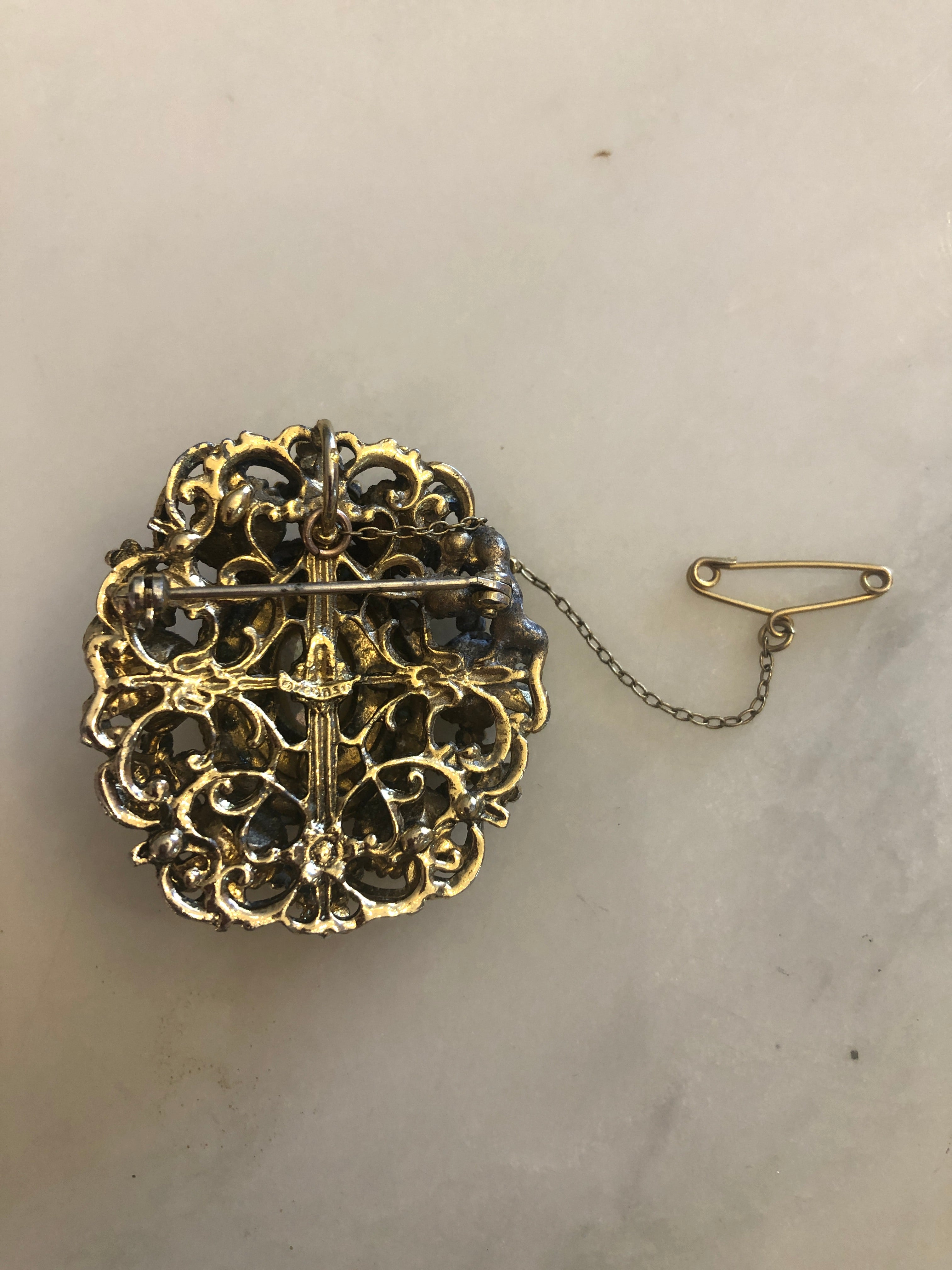 A 4cm x 4cm vintage Czech circular brooch featuring an oxidised and gold-tone openwork frame, a central mother of pearl oval cabochon surrounded by turquoise seed beads, eight blue marbled outer cabochons, white enamel flower accents, and an original gold-tone safety chain.