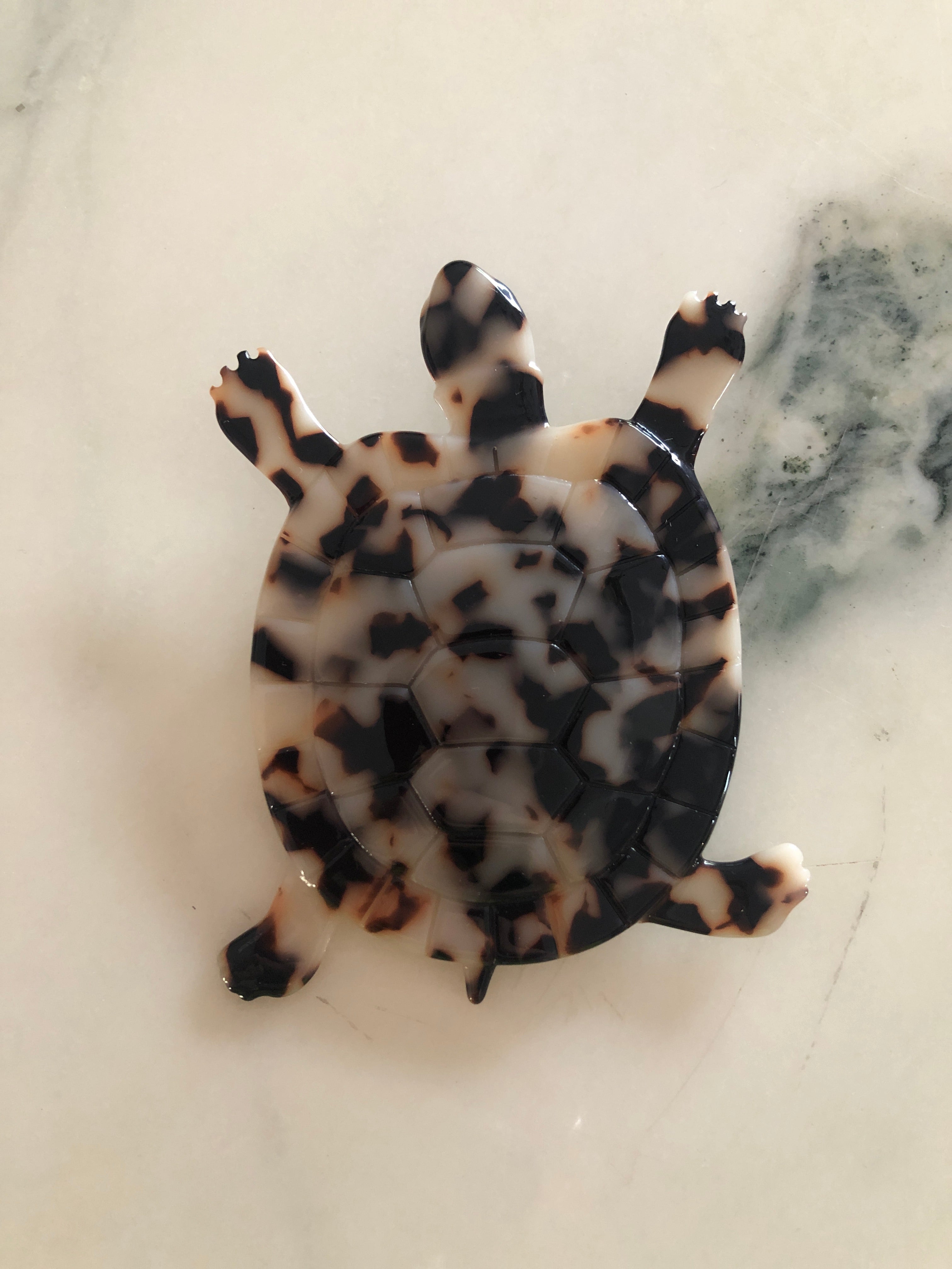 Men's tortoise brooch in brown tortoiseshell acetate. On a white marble surface