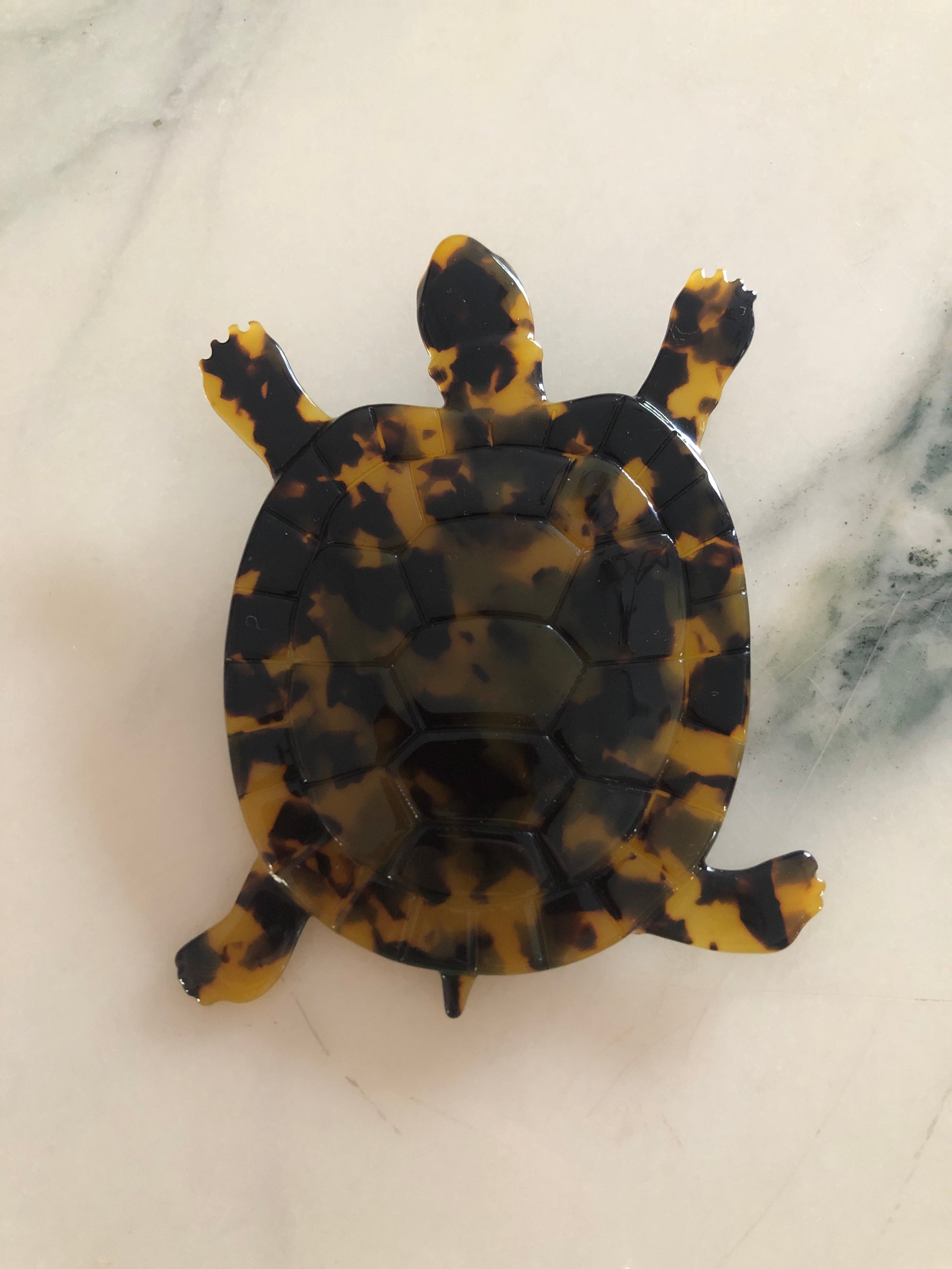 Men's tortoise brooch in brown tortoiseshell acetate. On a white marble surface