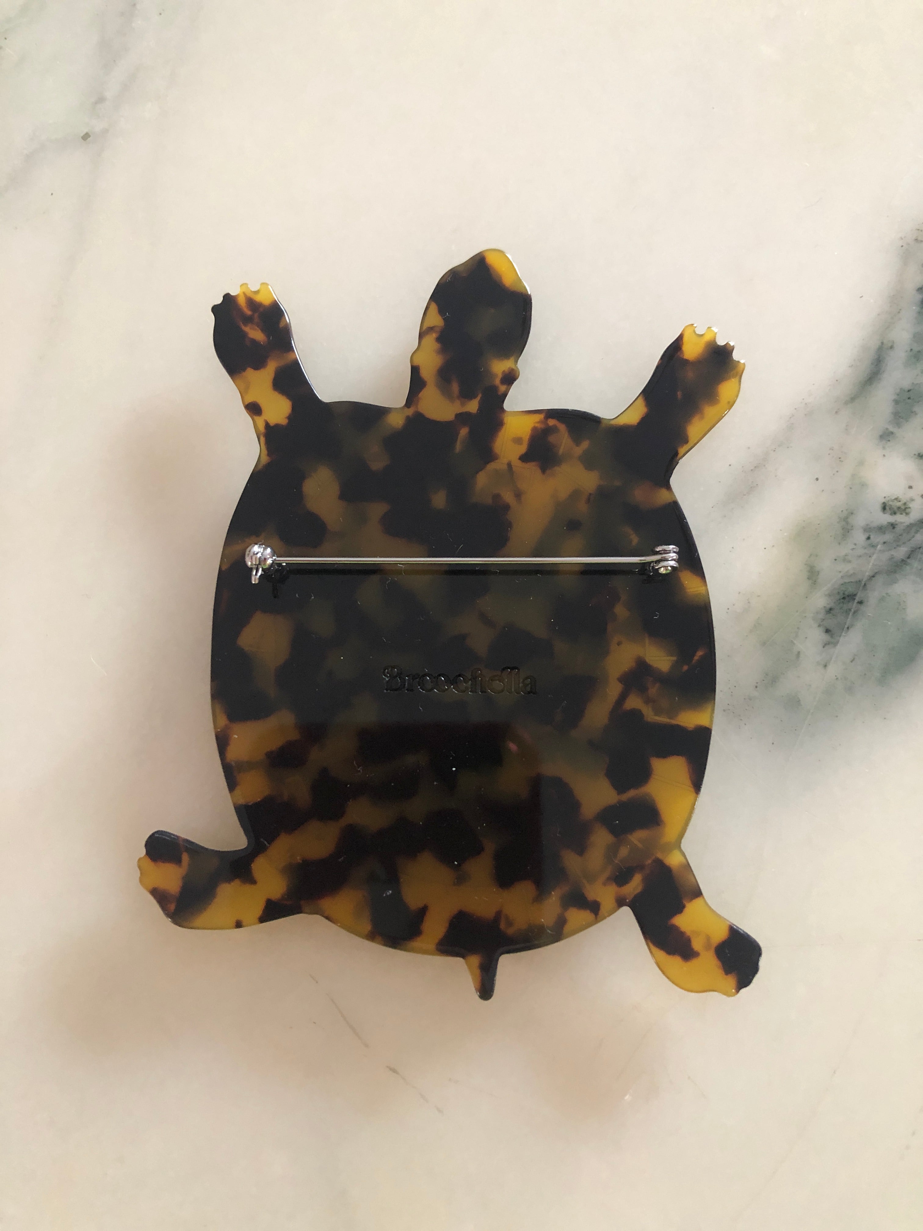 Men's tortoise brooch in brown tortoiseshell acetate. On a white marble surface