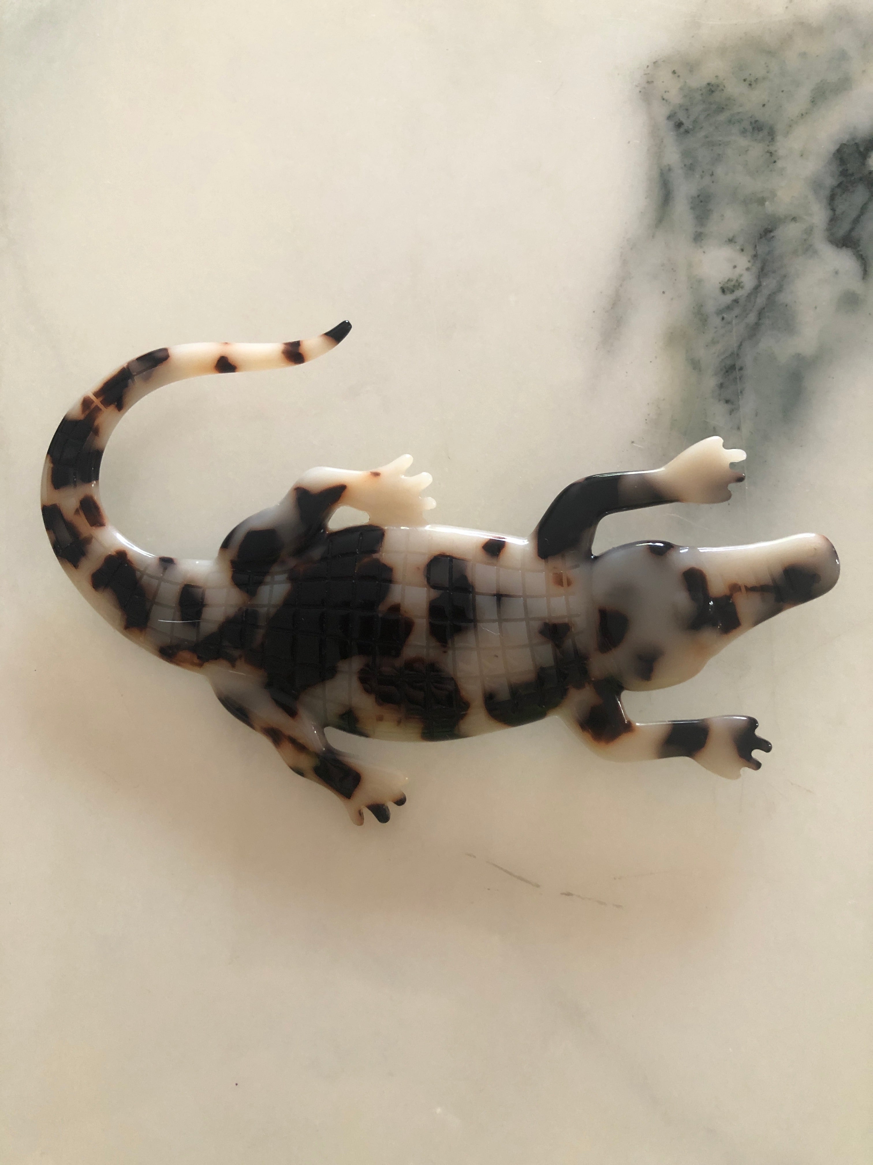 A Broochella Animalia Collection alligator brooch in brown tortoiseshell Italian cellulose acetate with detailed scale texture measuring 7cm x 12cm, photographed on a white marble surface.