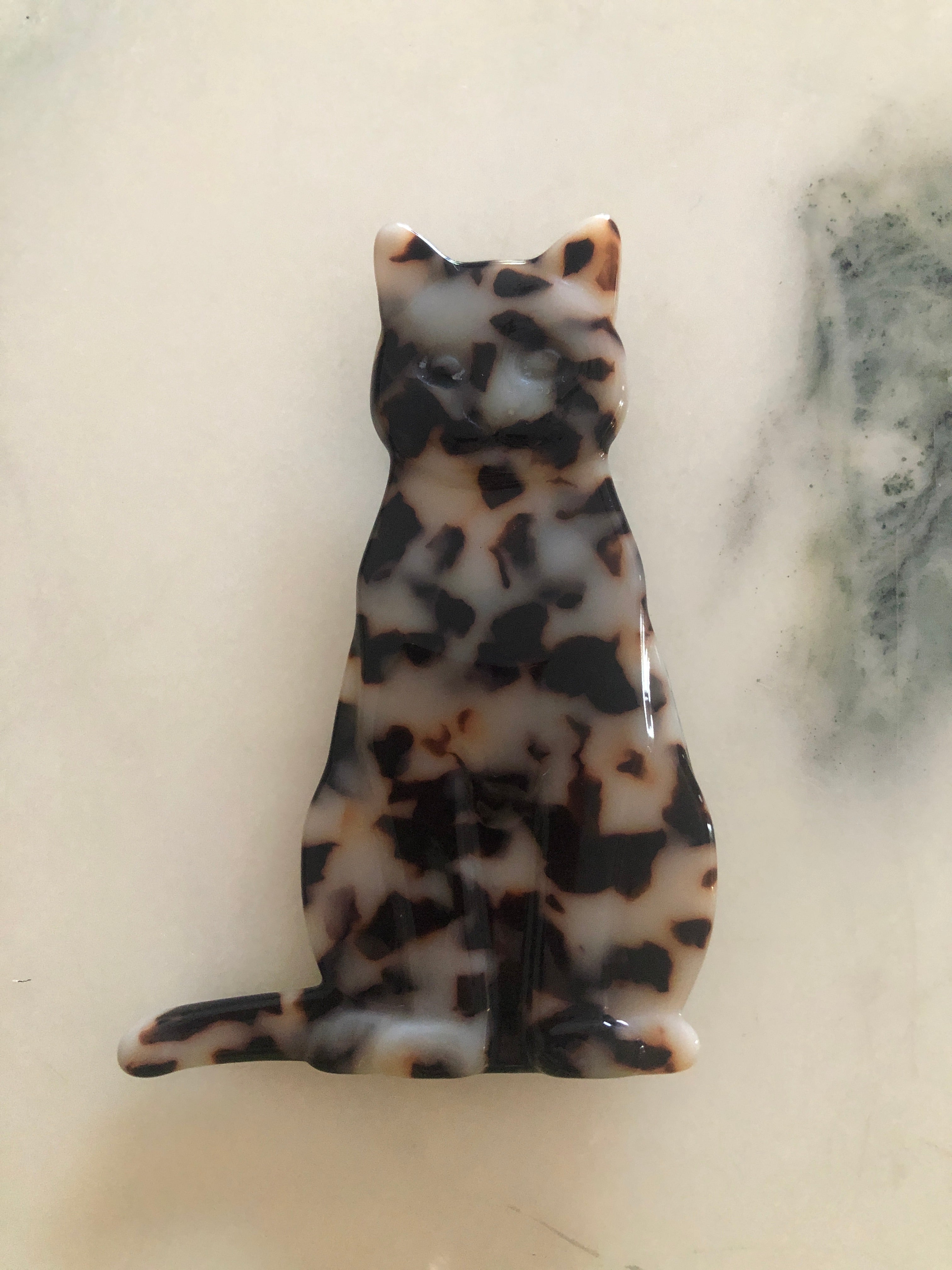 Men's cat brooch in brown tortoiseshell acetate. On a white marble background