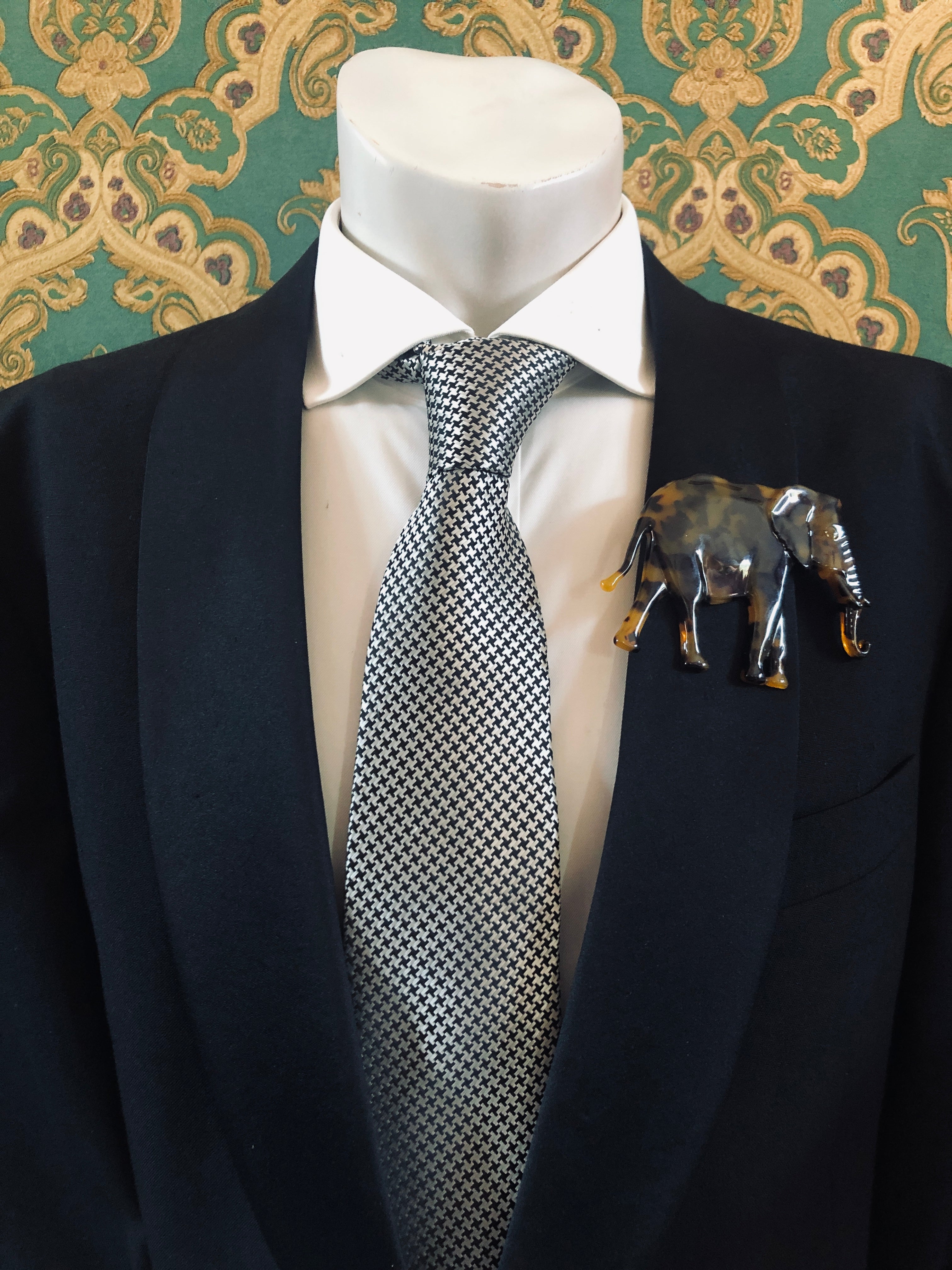 Men's elephant brooch in brown tortoiseshell acetate worn on a black tailored jacket with silver houndstooth tie, from the Broochella Animalia Collection.