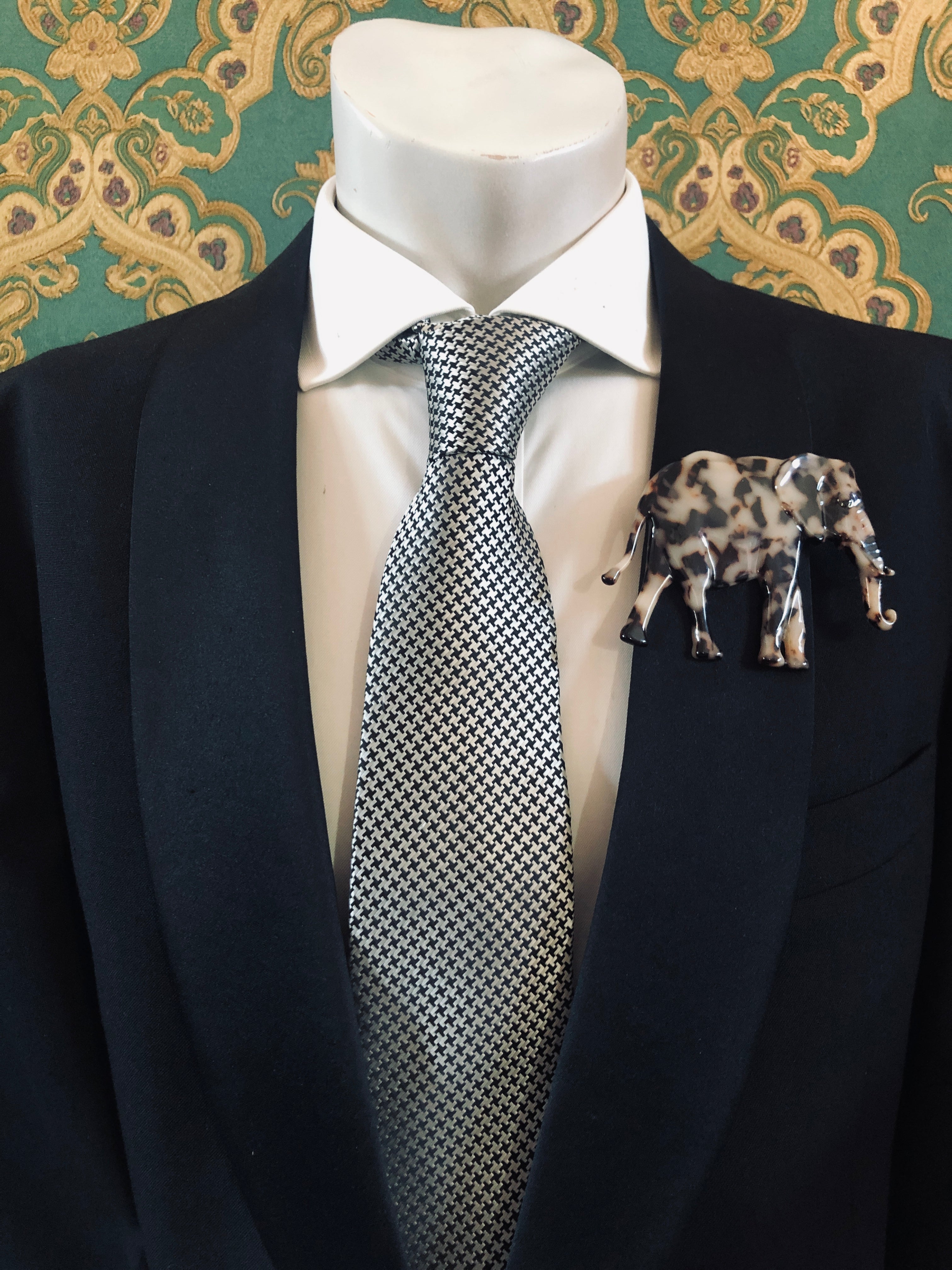 Men's elephant brooch in brown tortoiseshell acetate worn on a black tailored jacket with silver houndstooth tie, from the Broochella Animalia Collection.