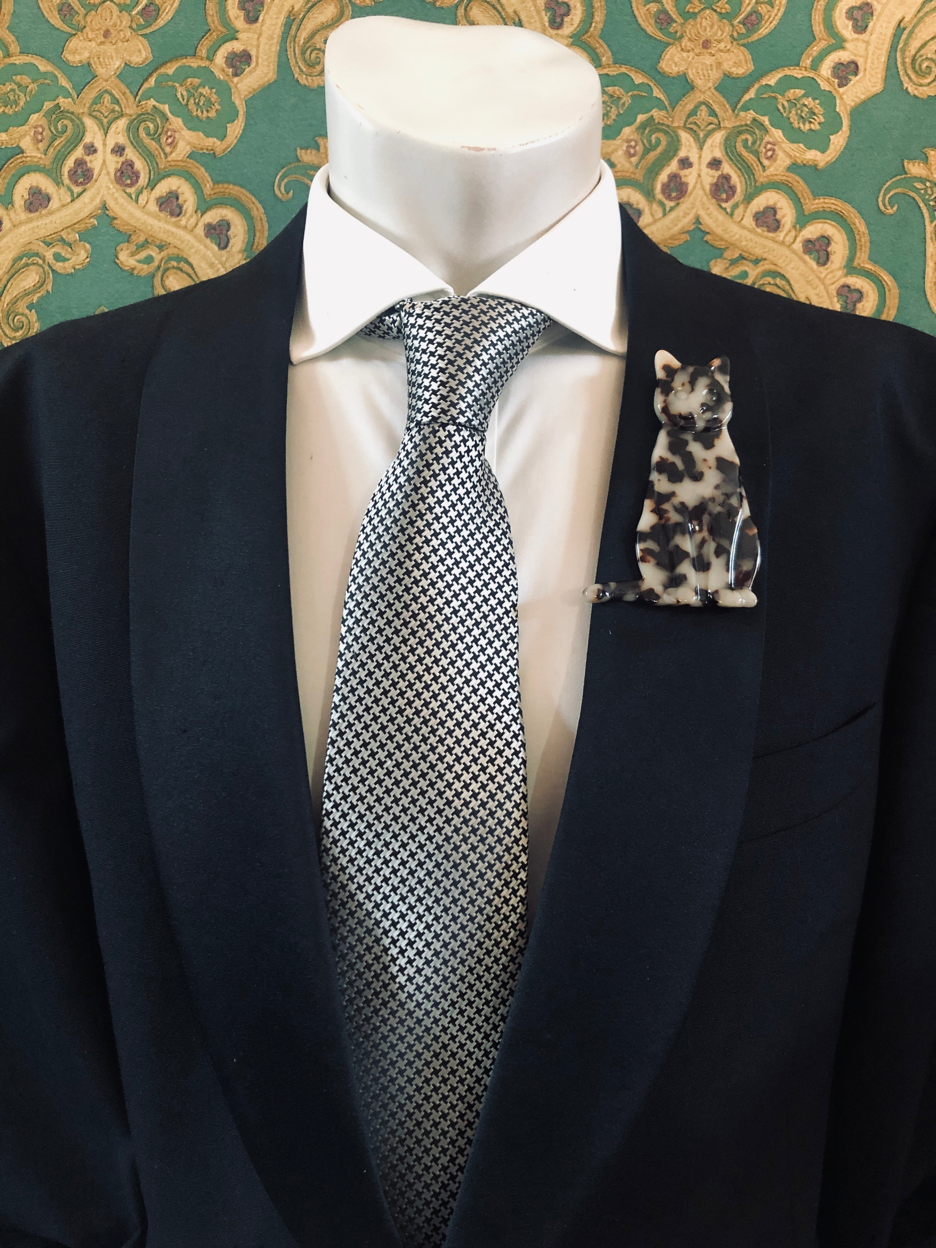 Men's cat brooch in brown tortoiseshell acetate worn on a black tailored jacket with silver houndstooth tie, from the Broochella Animalia Collection.