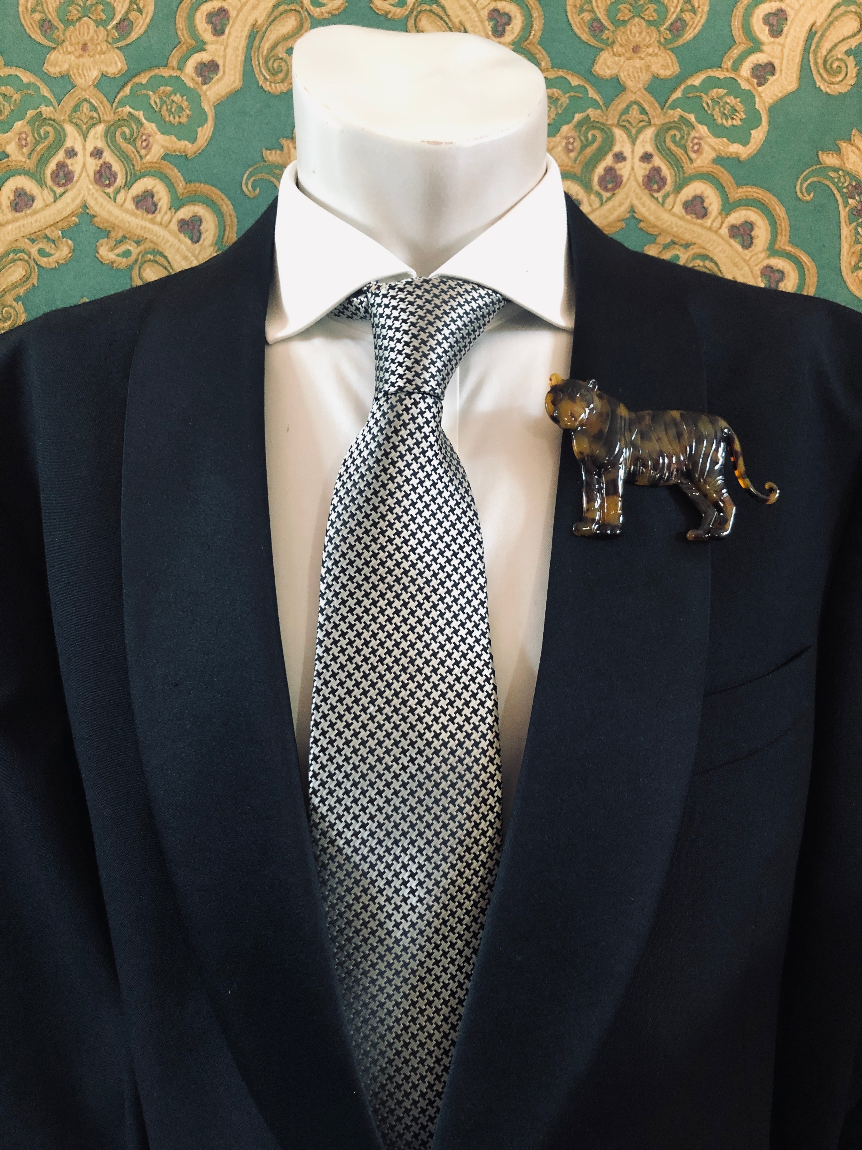 Men's tiger brooch in brown tortoiseshell acetate worn on a black tailored jacket with silver houndstooth tie, from the Broochella Animalia Collection.