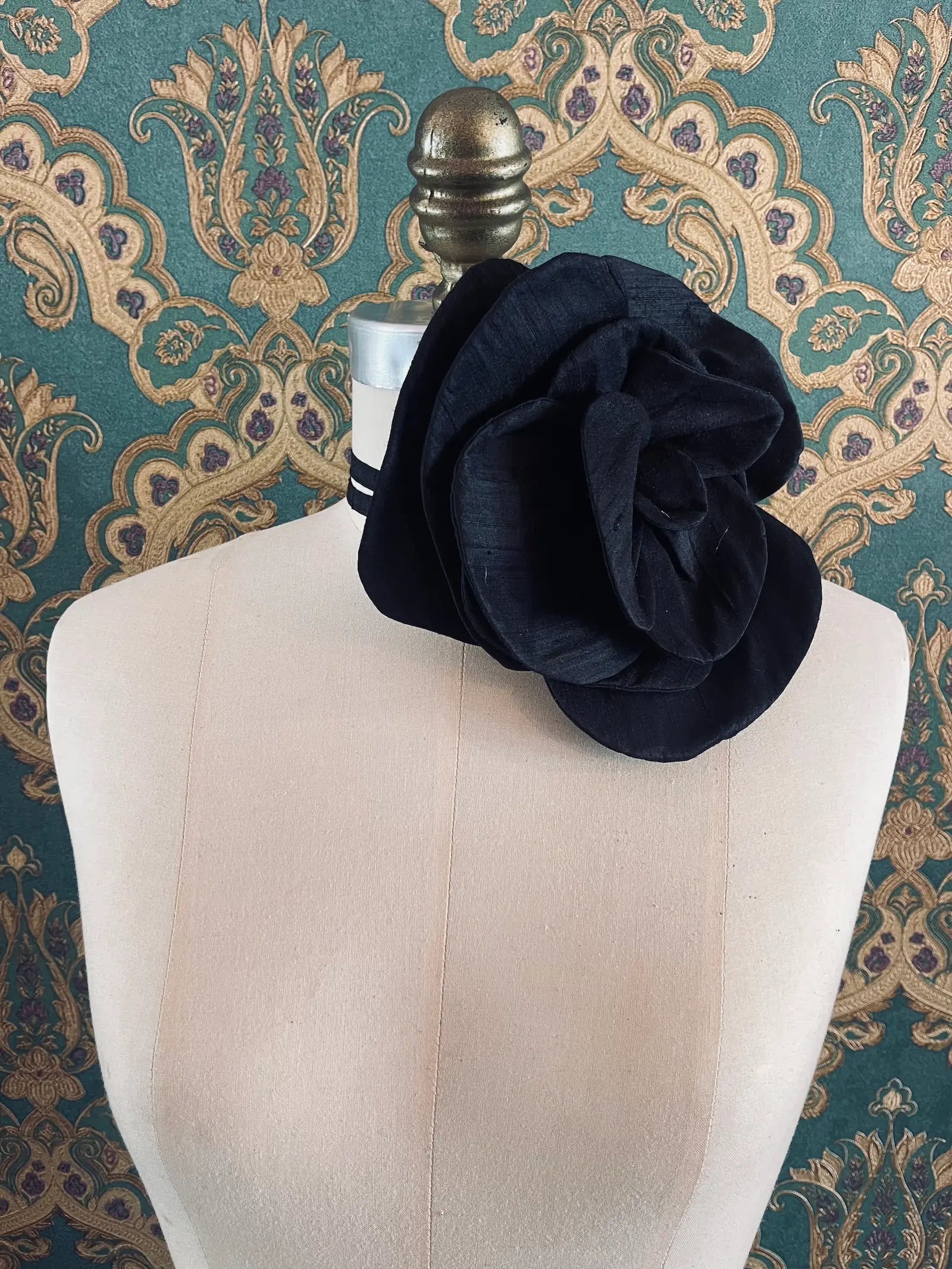Broochella Bellucci large black handmade silk flower brooch and choker  Pictured on a mannequin. The background is green and gold damask wallpaper.