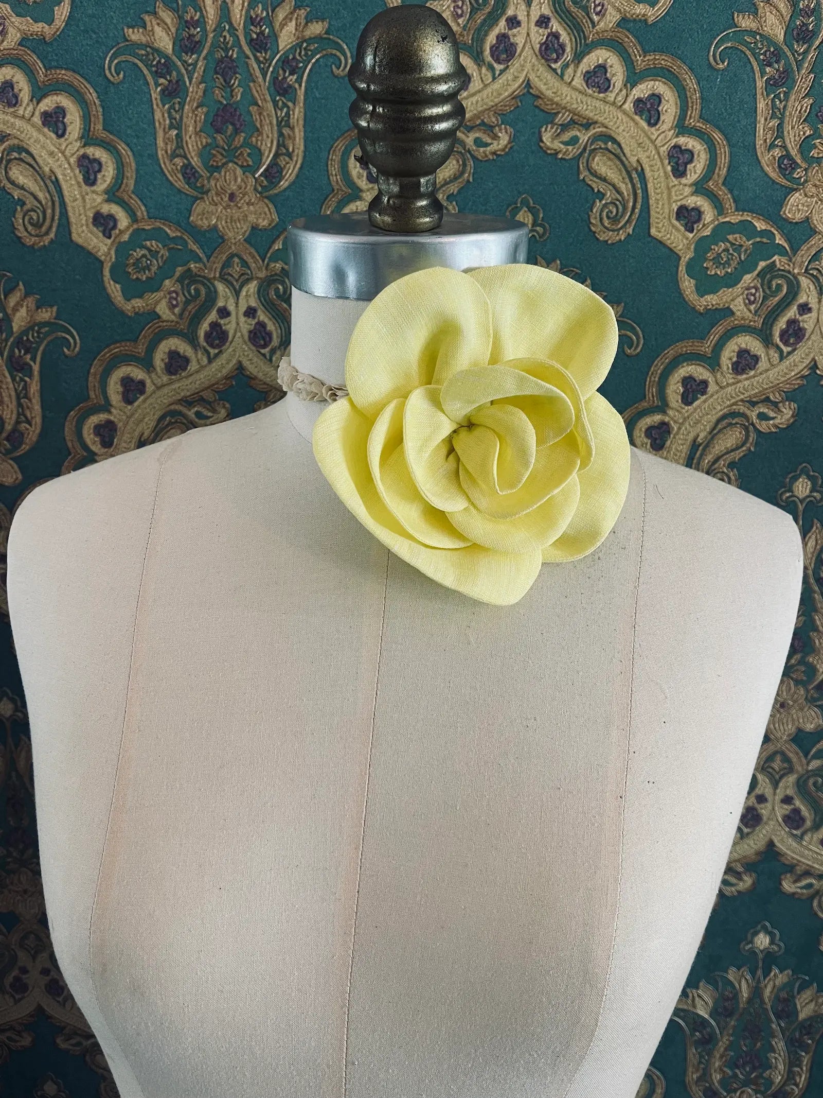 Broochella Florella small yellow handmade linen flower brooch and choker  Pictured on a mannequin. The background is green and gold damask wallpaper.
