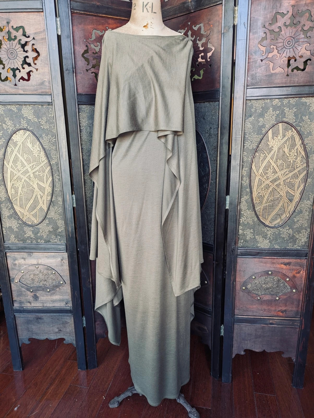 Broochella authentic designer Vintage Issey Miyake Draped Maxi Dress – Made in France. Size 36. Acrylic Wool Blend in Khaki. Pictured on a mannequin. The background is an ornate dark wood room divider.