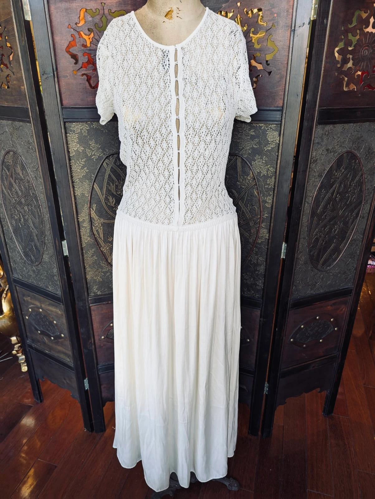 Broochella Bec and Bridge maxi dress with short sleeves and a lace bodice. It is displayed  on a mannequin against a decorative screen