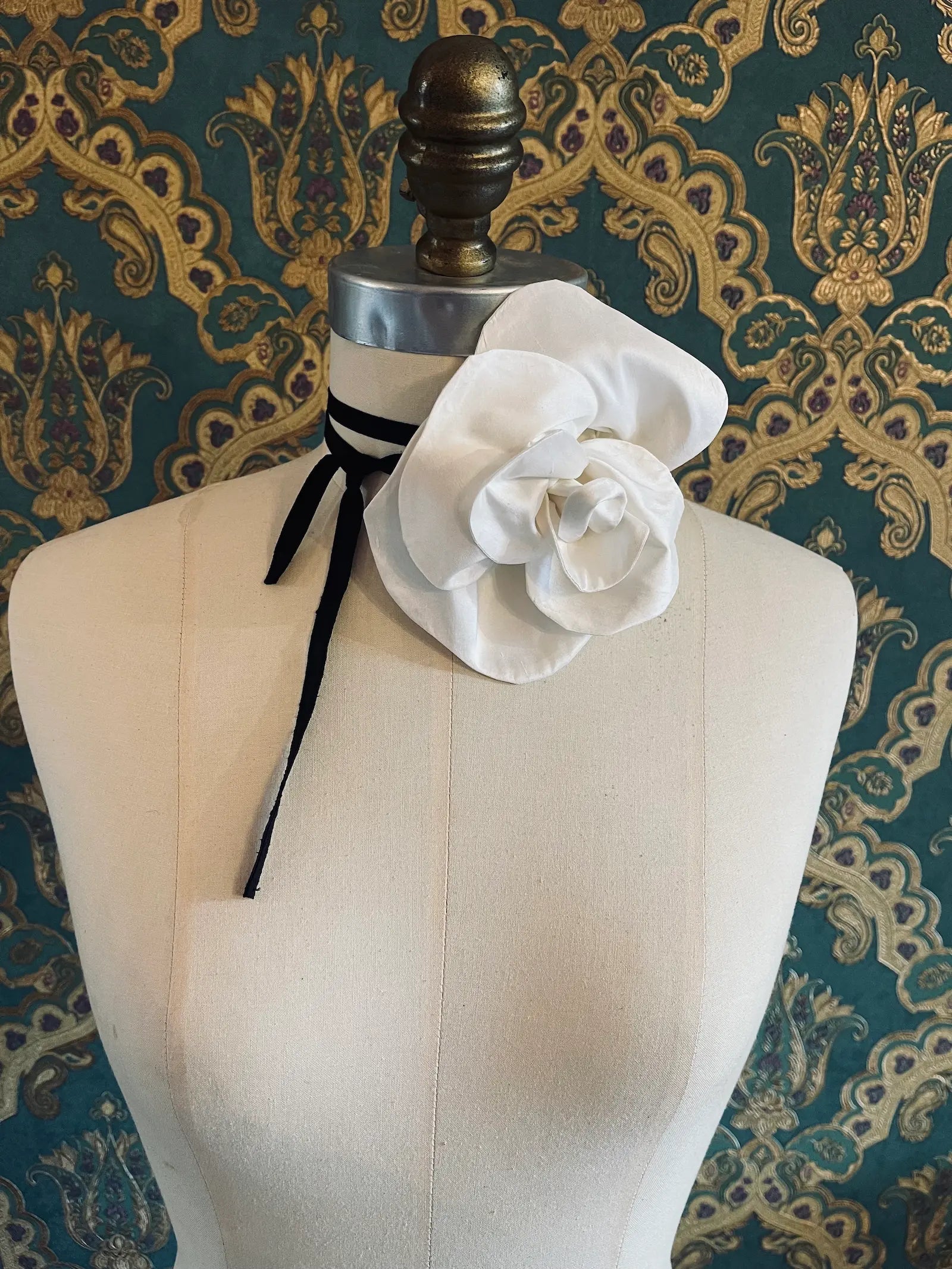 Broochella Bellucci small ivory handmade silk flower brooch and choker  Pictured on a mannequin. The background is green and gold damask wallpaper.
