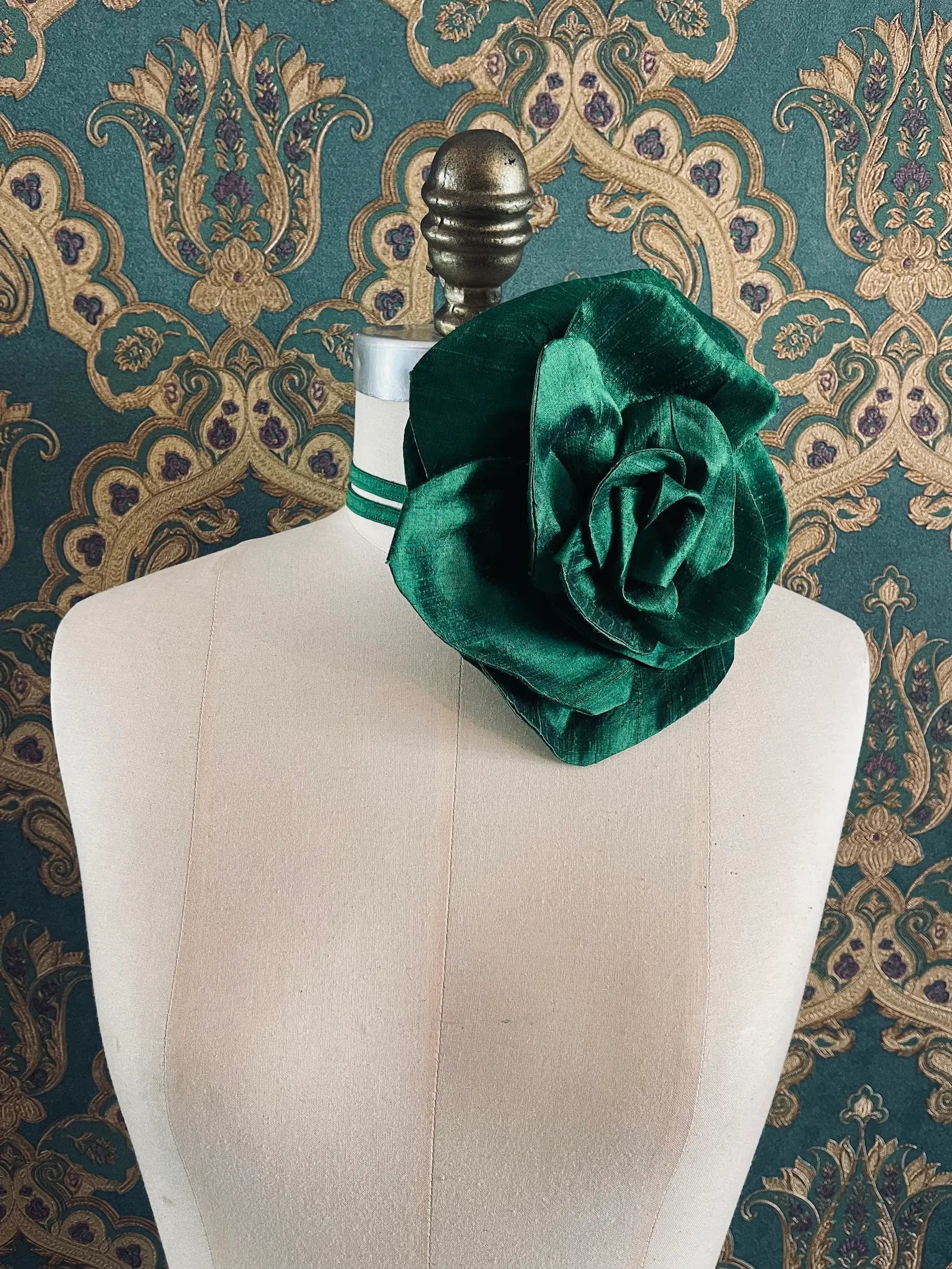Broochella Bellucci large green handmade silk flower brooch and choker  Pictured on a mannequin. The background is green and gold damask wallpaper.
