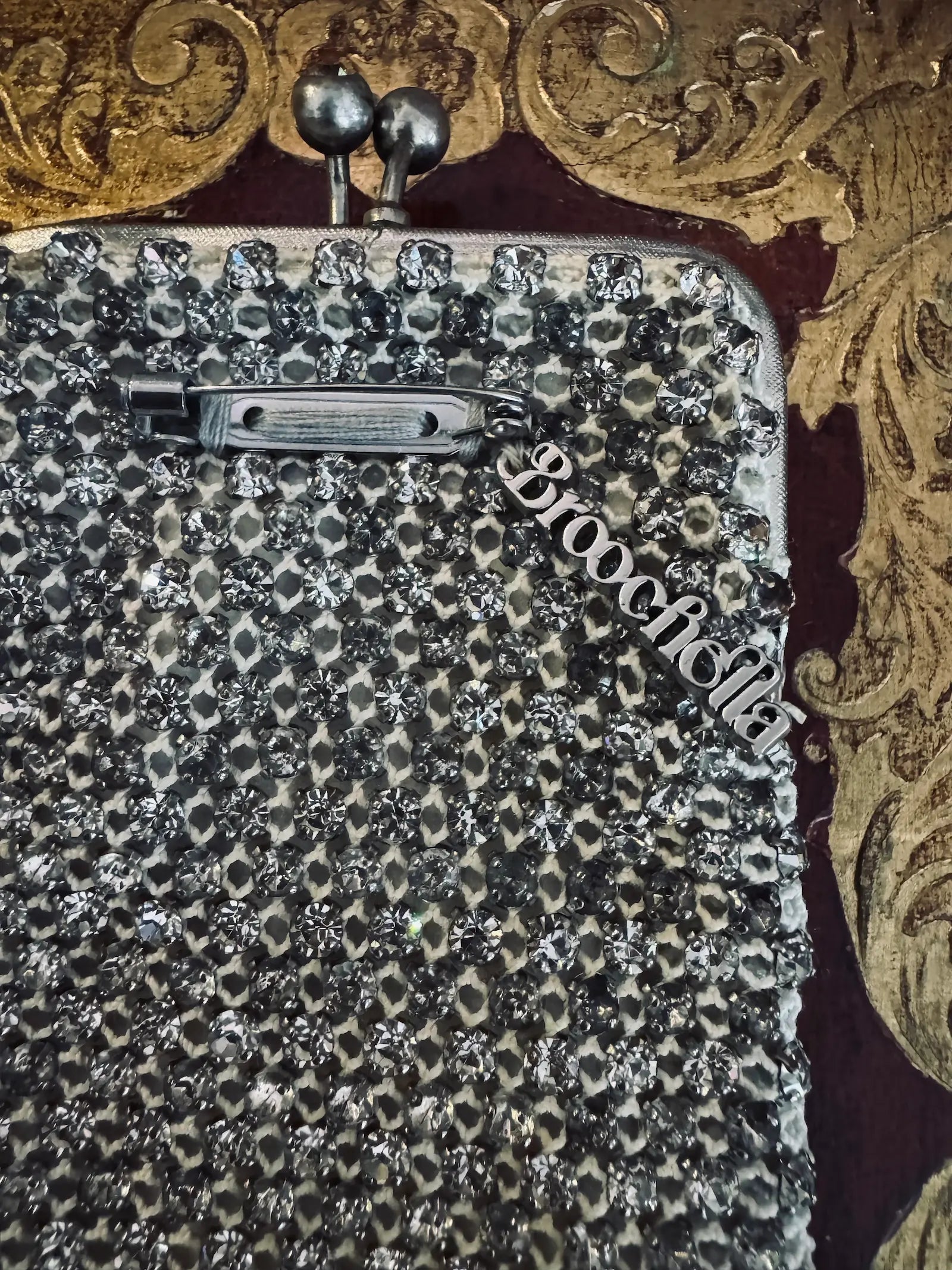 Mannequin wearing a black coat with a sparkling handbag and white shirt with decorative collar. It is wearing the Broochella Borsellino vintage crystal purse brooch. 