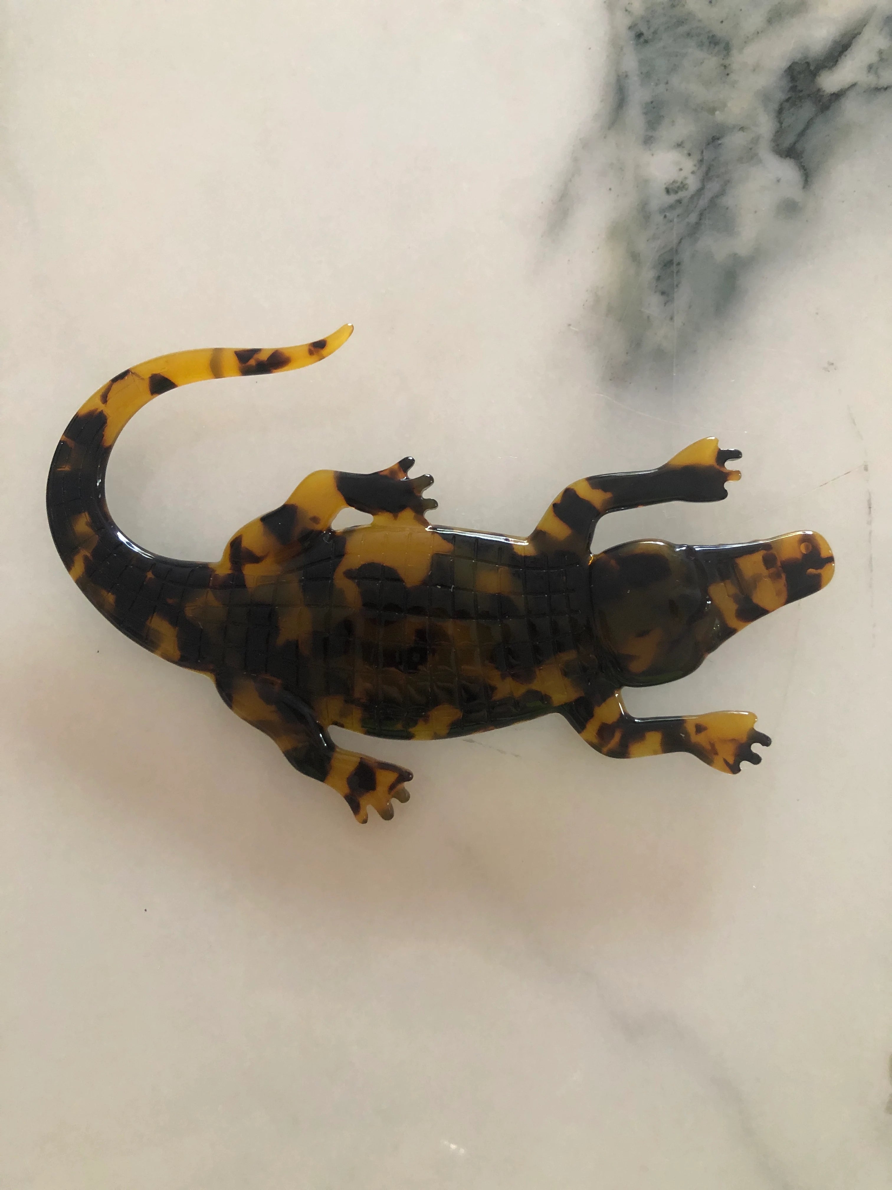 Broochella animalia collection brown and black tortoiseshell crocodile handmade designer cellulose acetate brooch.  Pictured on a white marble table
