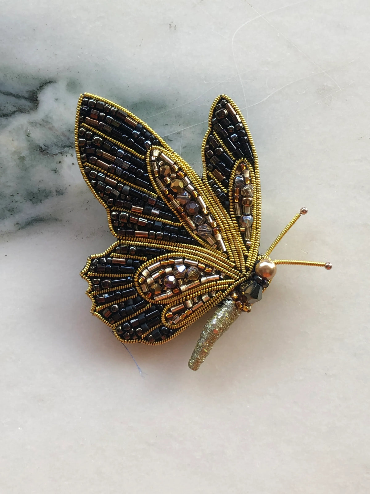 Broochella Butterfly Brooch Pin hand-beaded in black, gold and bronze with crystals, metallic beadwork and sculptural wings.