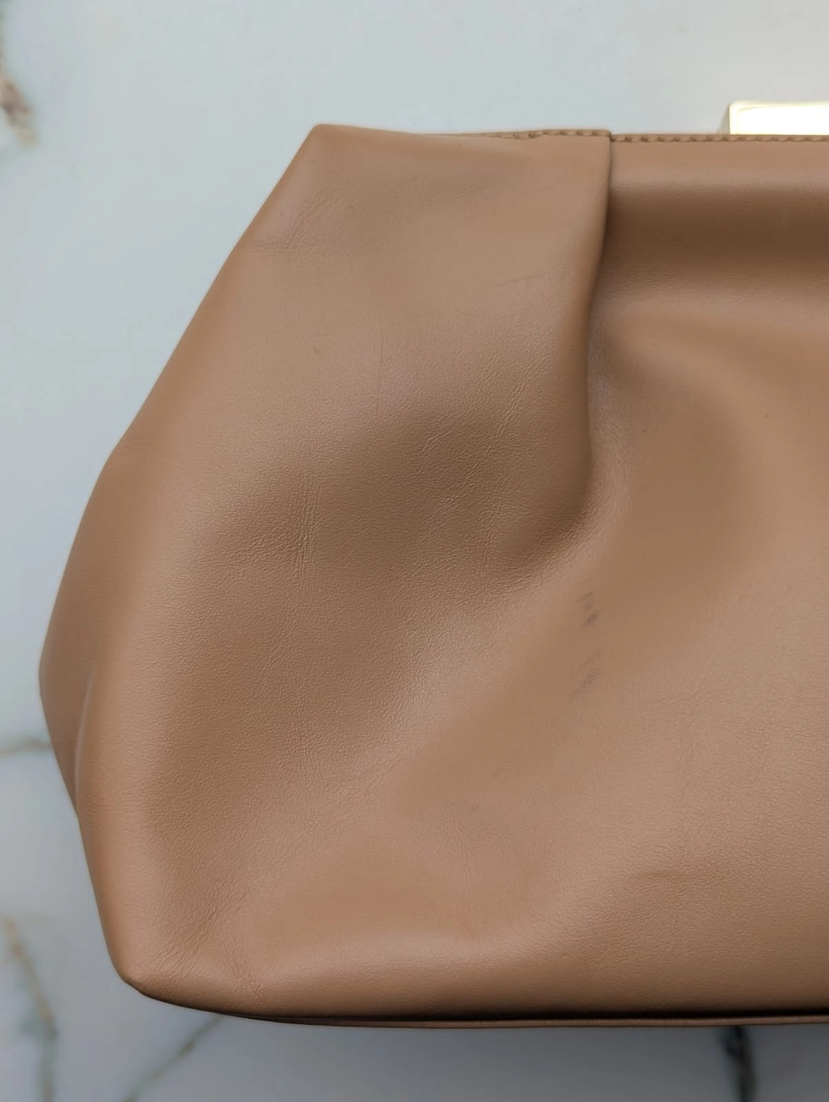 Broochella The Stylist's Closet De Mellier designer brown leather bag. Pictured on a white marble surface