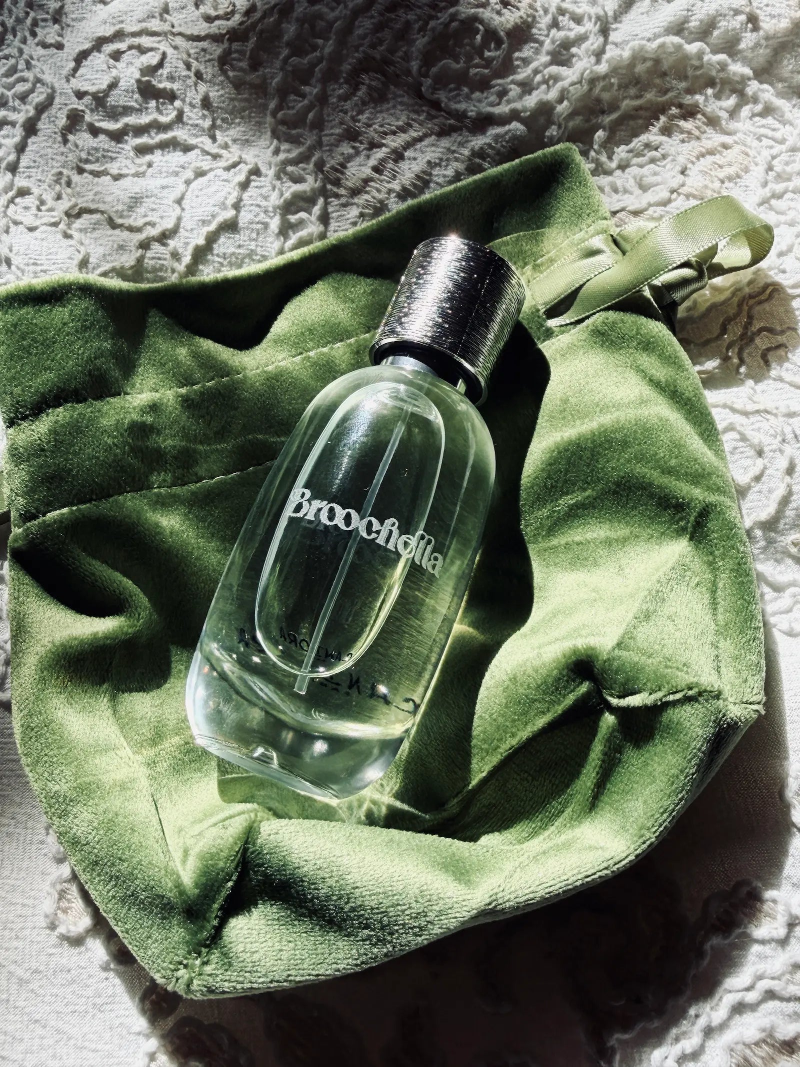 Broochella eu du Parfum bottle on a green velvet bag. 