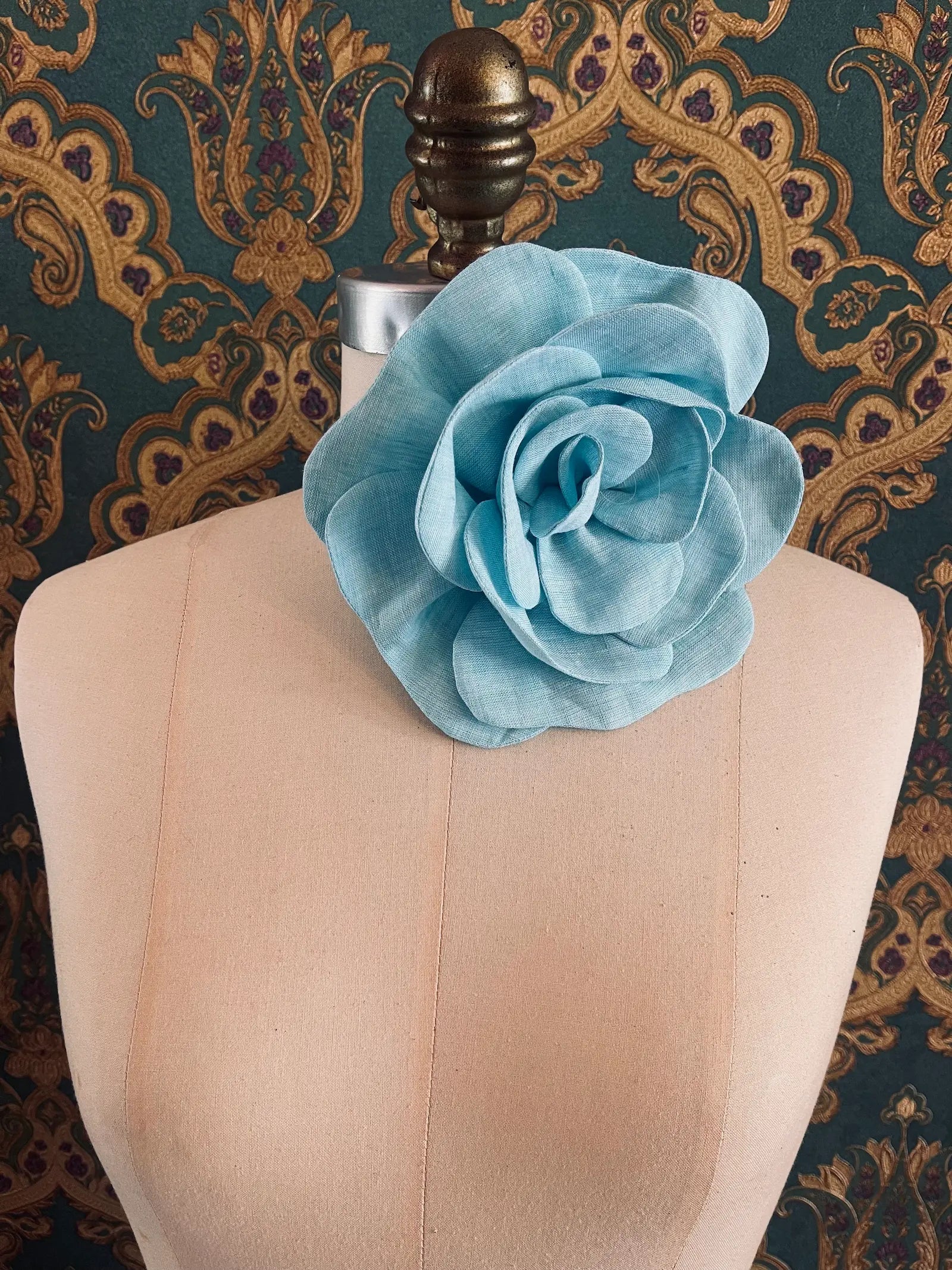 Broochella Florella large blue handmade linen flower brooch and choker  Pictured on a mannequin. The background is green and gold damask wallpaper.