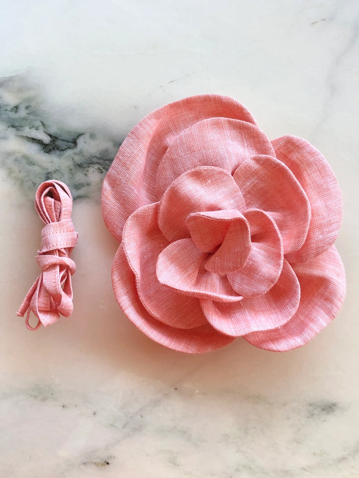 Broochella Florella small orange linen flower choker and brooch with matching ribbon, photographed on a white marble background.