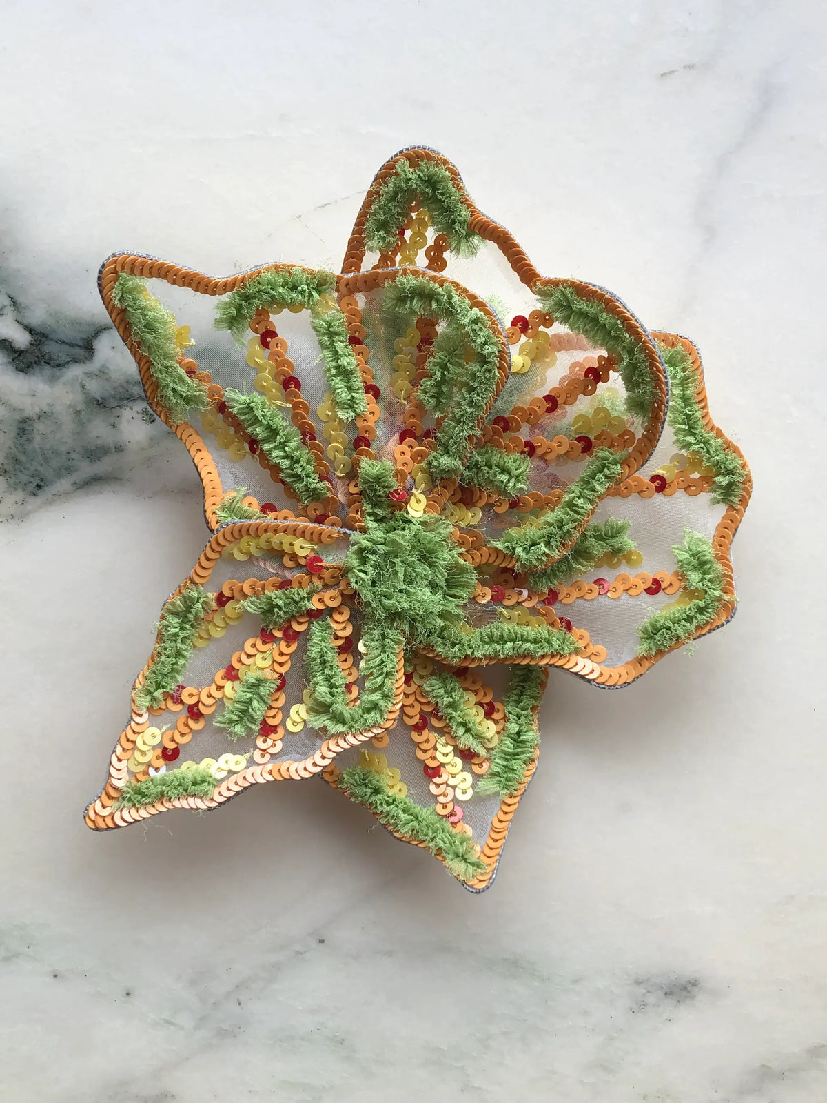 Broochella Men's Giglio di Tigre Small Flower Brooch Pin in green, featuring sculptural sheer petals embellished with orange and yellow sequins, textured lime green embroidery and a raised floral centre. A statement hand-embellished flower brooch for jackets, dresses and contemporary styling.