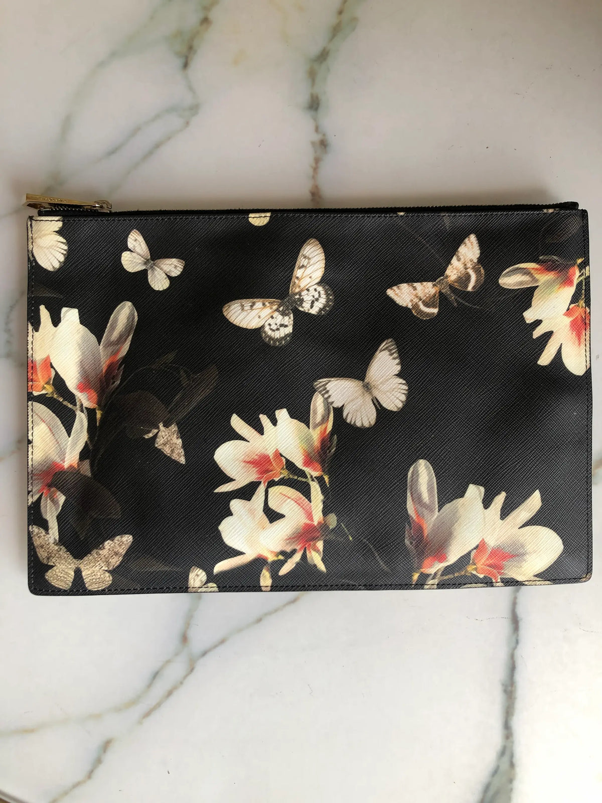 Genuine Givenchy black coated-canvas zip pouch featuring the Resort 2015 magnolia flower and butterfly print. Pictured on a white marble surface.