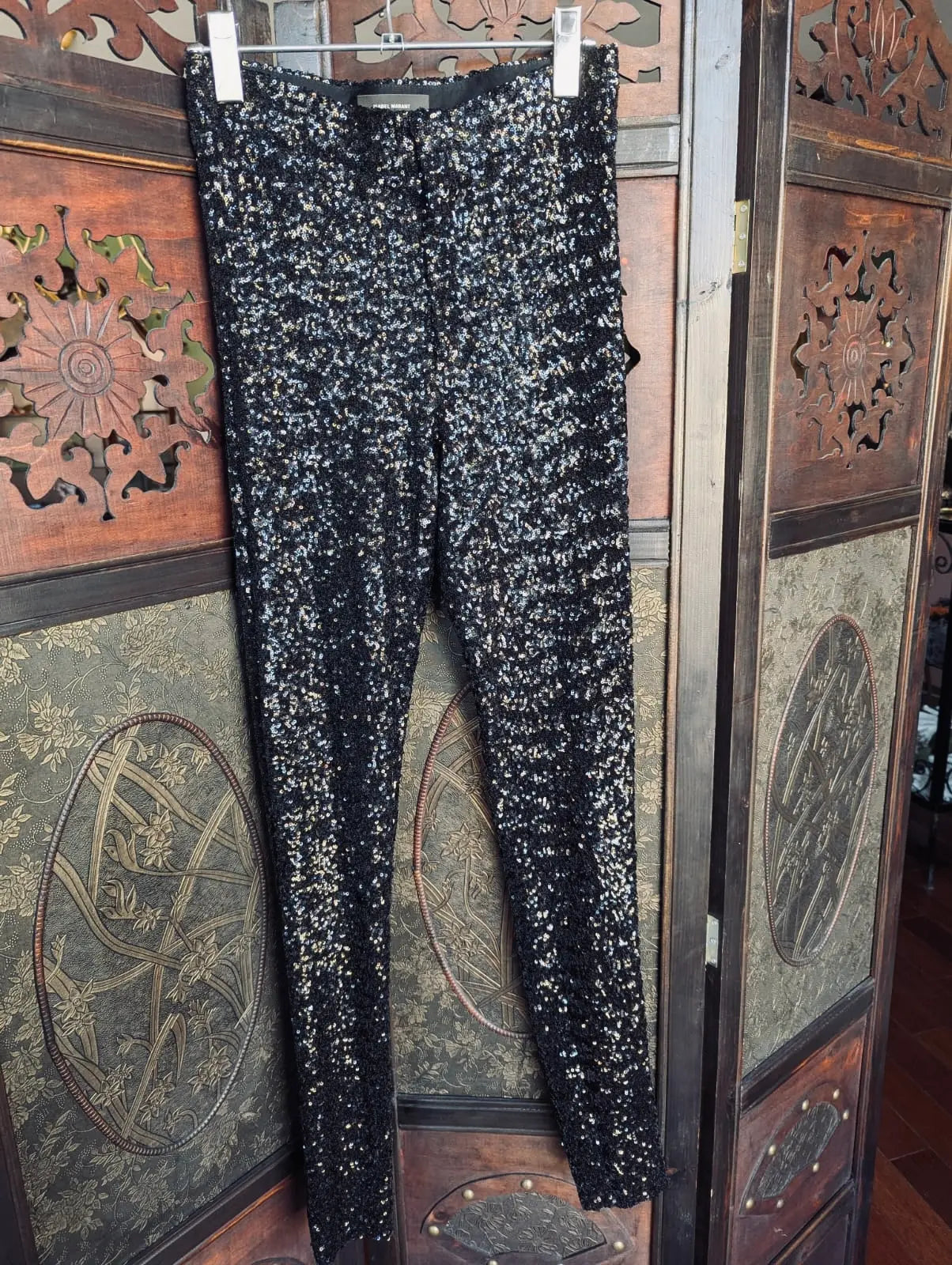 Isabel Marant Black Sequin fitted  pants – Size 36. They are hanging over a decorative dark wood room divider. 