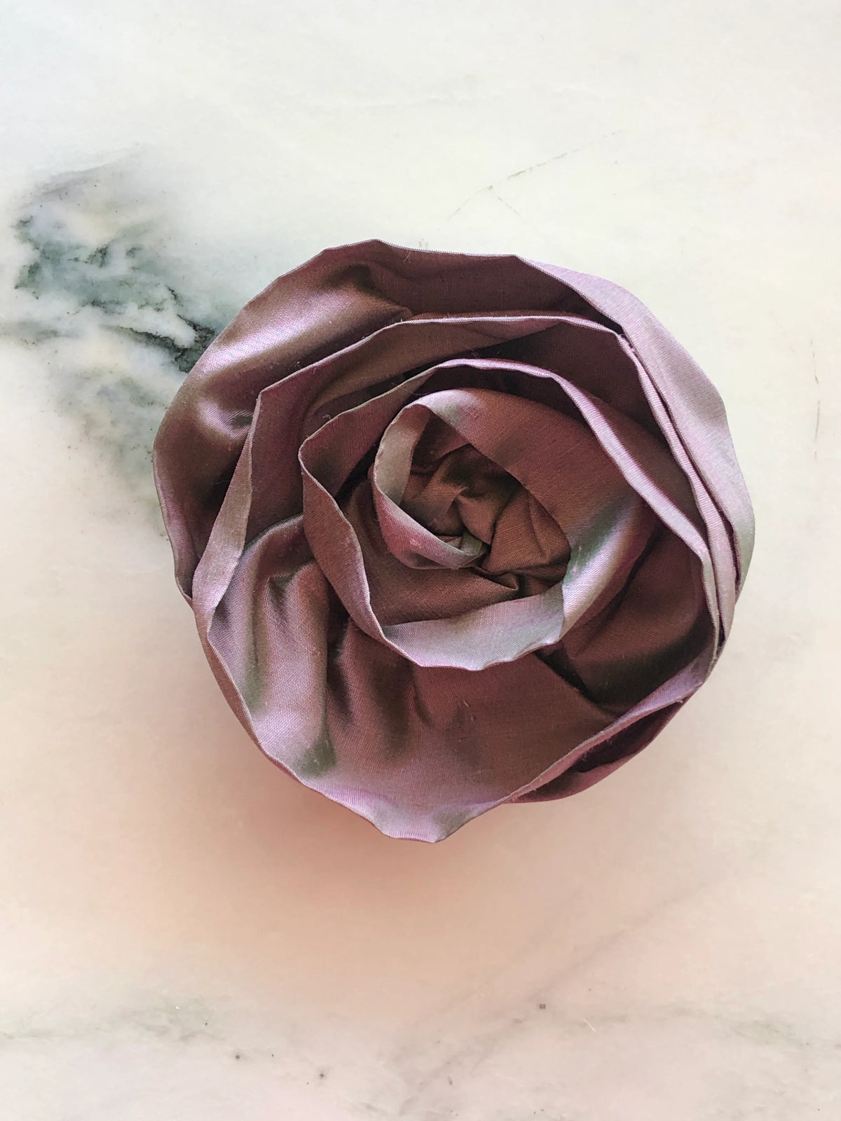 Handmade Broochella Isabella Rossellini designer silk rosette brooch for men in rich violet, featuring sculptural layered petals for statement menswear styling, photographed on white marble.