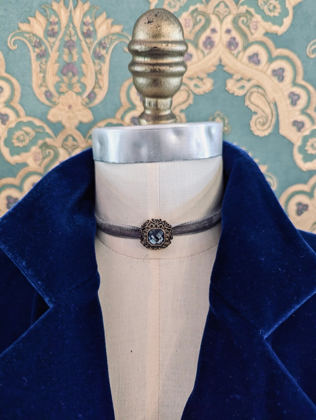 Broochella silver lady whistledown velvet choker with crystal embellishment.  Pictured on a mannequin.  The background is green and gold damask wallpaper