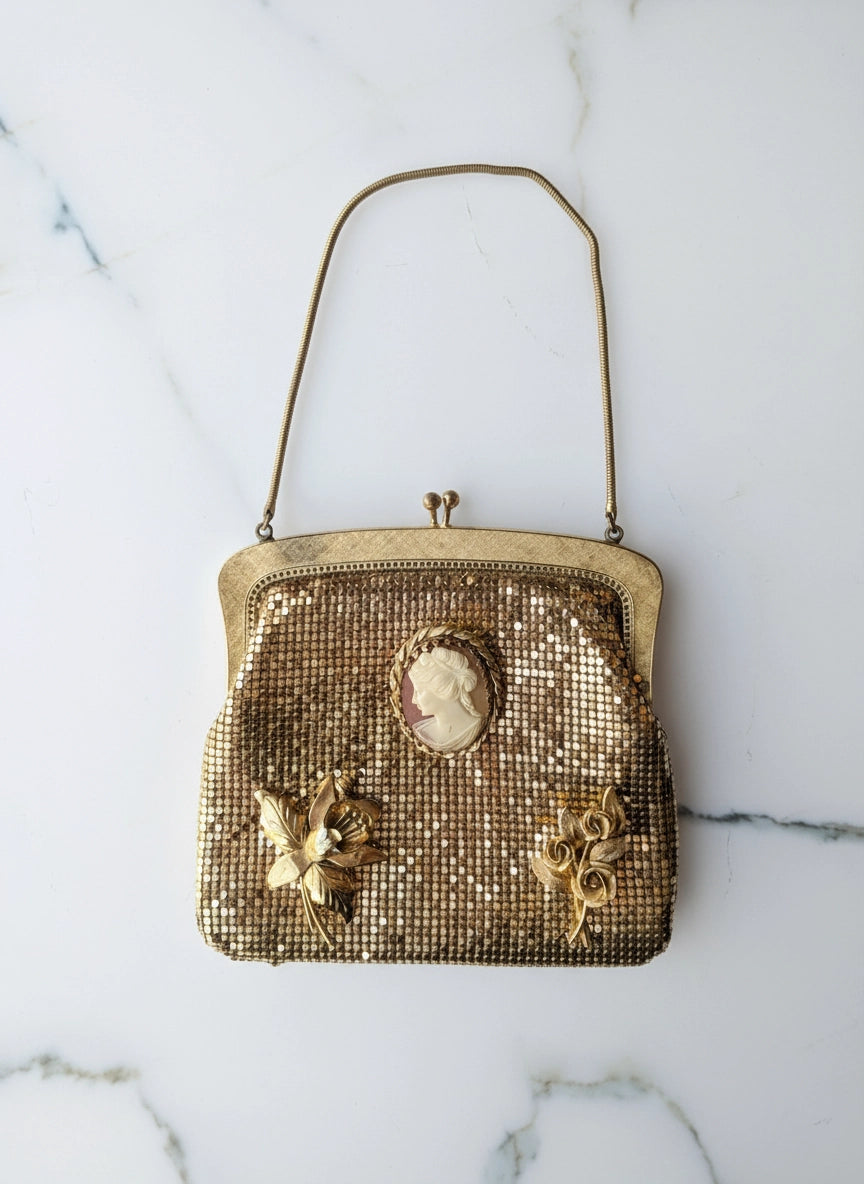 Broochella  la dame d'or oroton gold, glomesh vintage bag with vintage brooch embellishments. The background is white marble