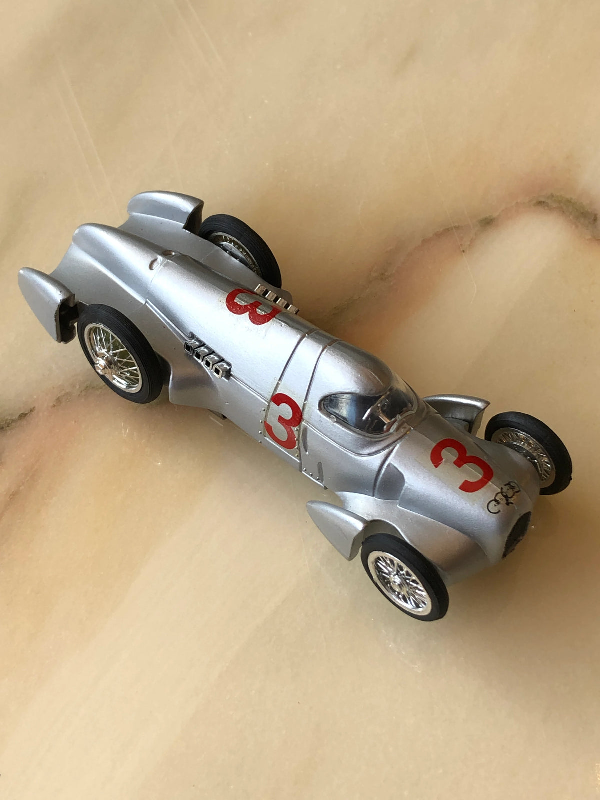 Broochella Men's Argento No.3 Vintage Formula One Racing Car Brooch in metallic silver, featuring red number 3 racing decals, streamlined bodywork, chrome wire-spoke wheels and a clear cockpit windscreen.