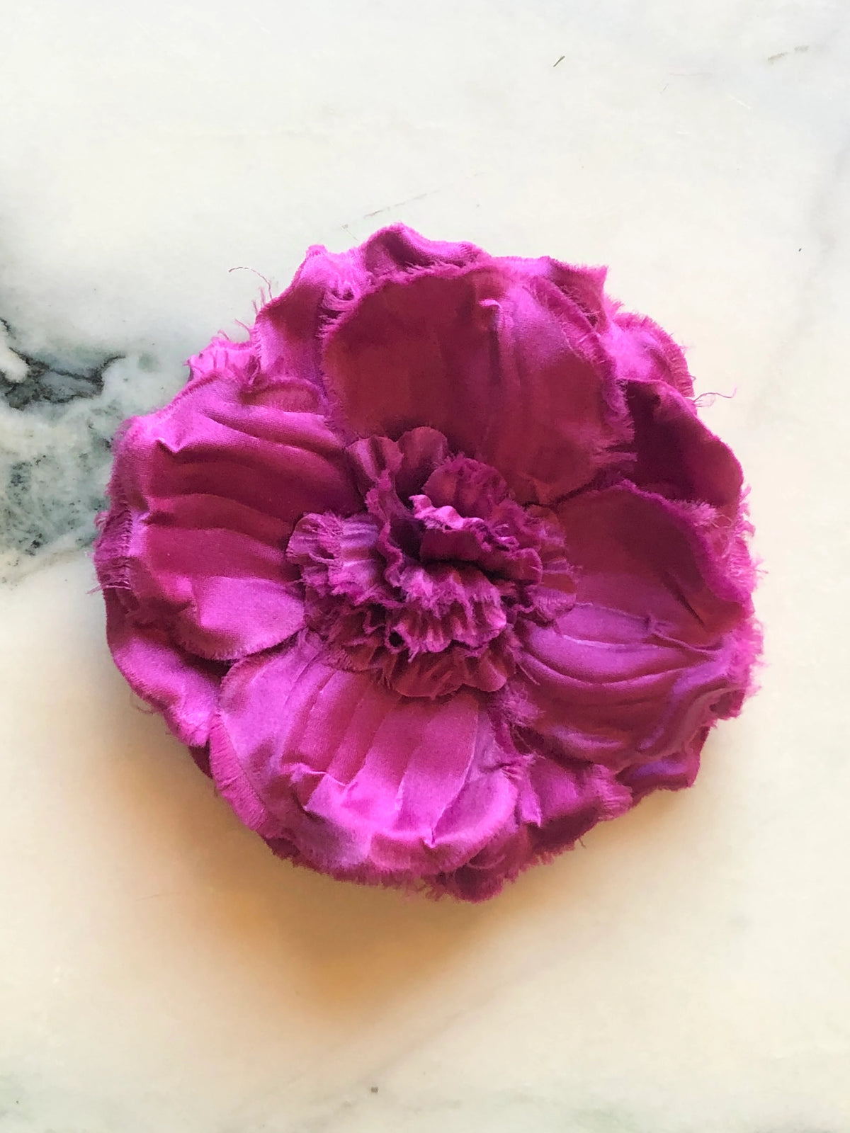 Broochella Men’s Malva Flower Brooch in vivid pink, a handmade designer fabric flower with layered raw-edge petals and a textured ruffled centre, photographed on white marble.