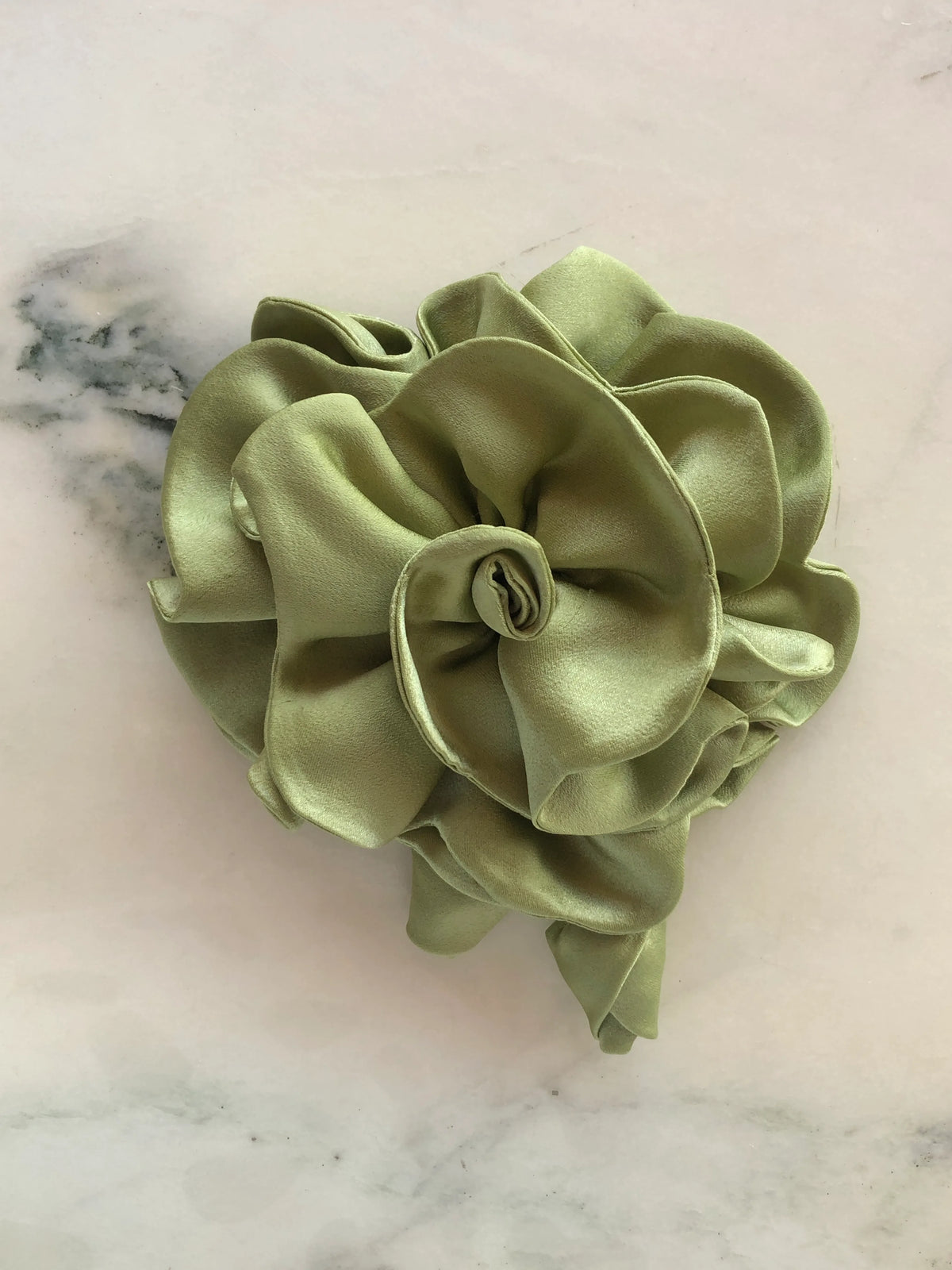 Broochella handmade designer satin Rosetta flower brooch in avocado with sculptural layered petals and trailing flower buds, photographed on white marble.