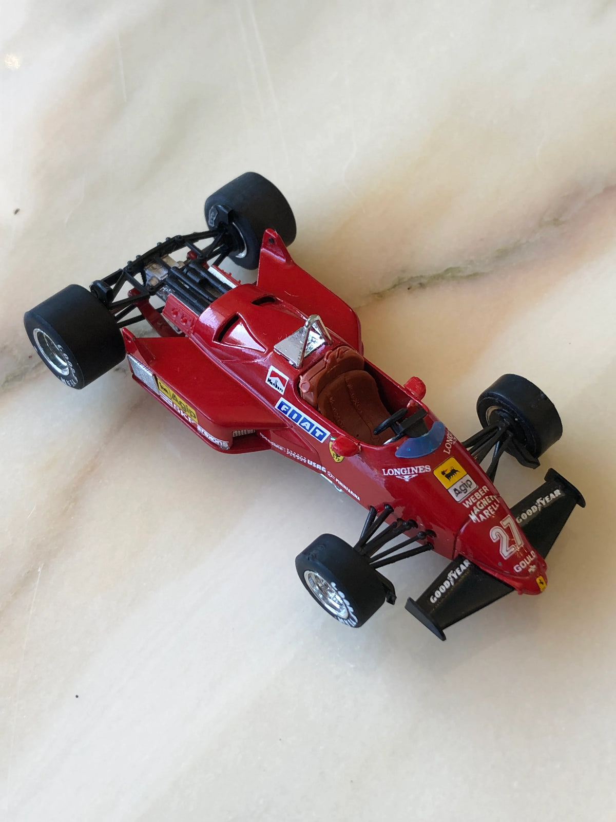 Broochella Men's Rosso Maranello No.27 Ferrari Formula One Racing Car Brooch in glossy red, featuring a vintage open-wheel design, brown cockpit seat, black racing tyres, Ferrari shield and sponsor decals.