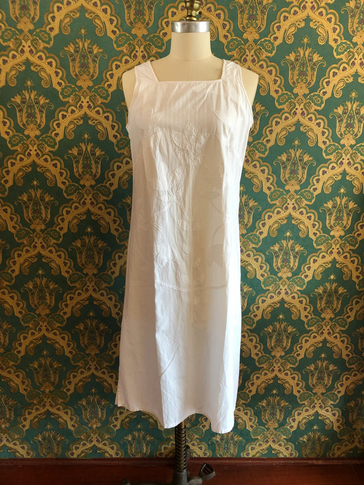 Broochella Mid summer Australia white striped cotton maxi dress with tonal leaf appliqué, size Small. Pictured on a mannequin. The background is green and gold damask wallpaper