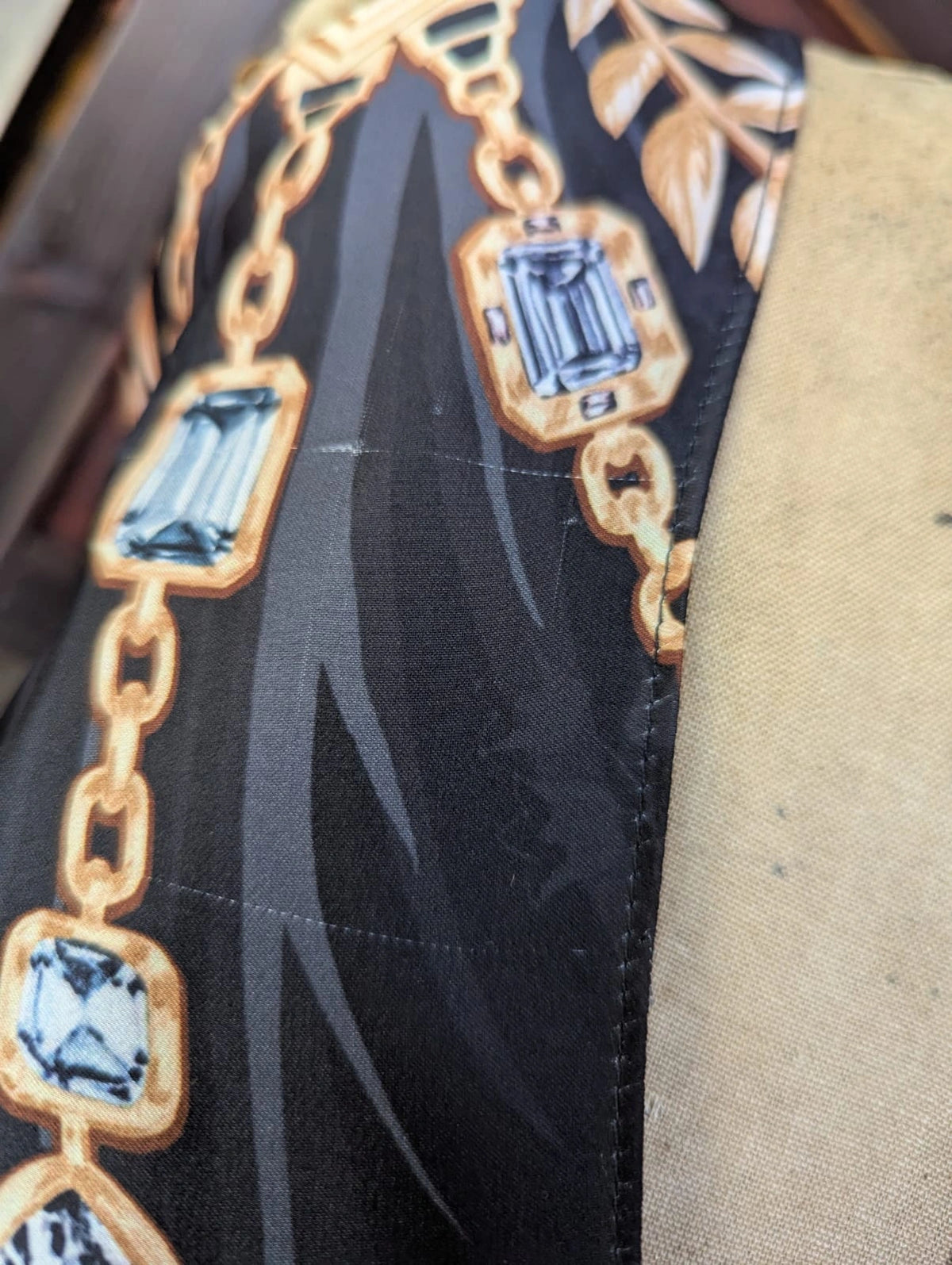 Broochella Paco Rabanne maxi dress.  Close-up of a flaw in fabric. The fabris is black and the print is gold chain with blue gemstones. 