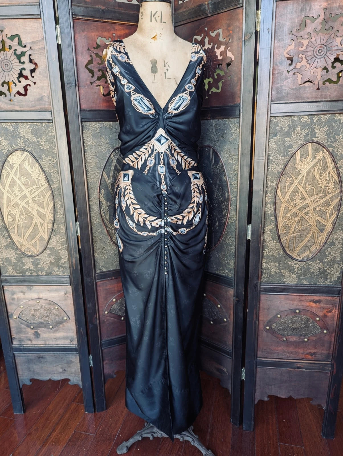 Broochella Paco Rabanne authentic designer black satin maxi dress with gem and flower print. Decorative black evening gown on a mannequin against an ornate wooden wall.