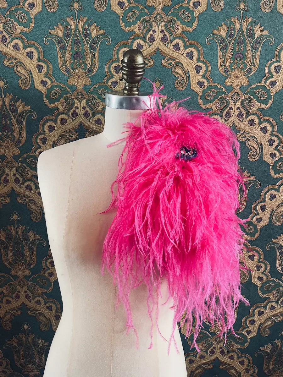 Broochella Piuma handmade neon pink feathered embellished designer brooch pictured on a mannequin the background is green and gold damask wallpaper