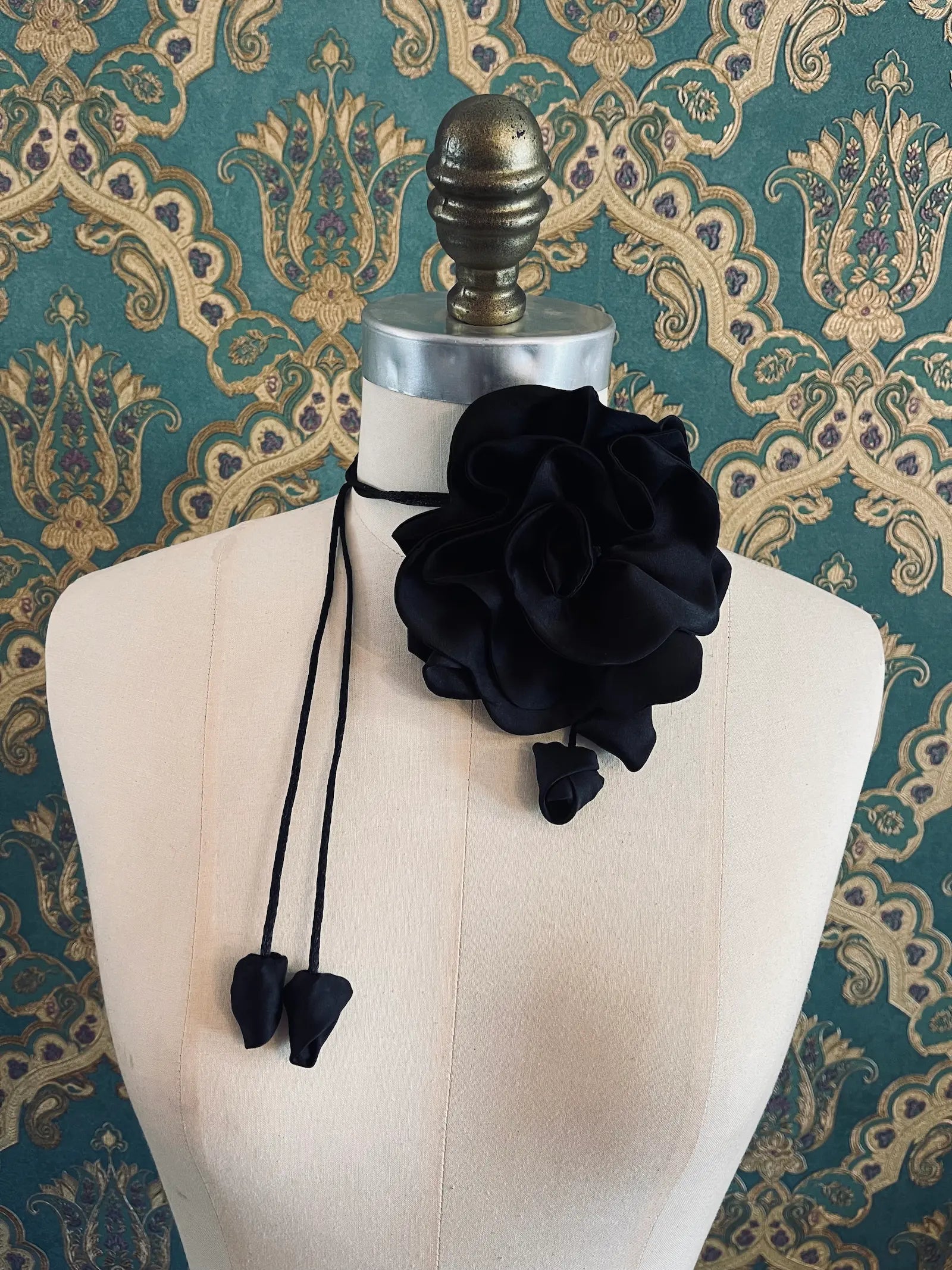 Broochella Rosetta black handmade silk satin flower brooch and choker  Pictured on a mannequin. The background is green and gold damask wallpaper