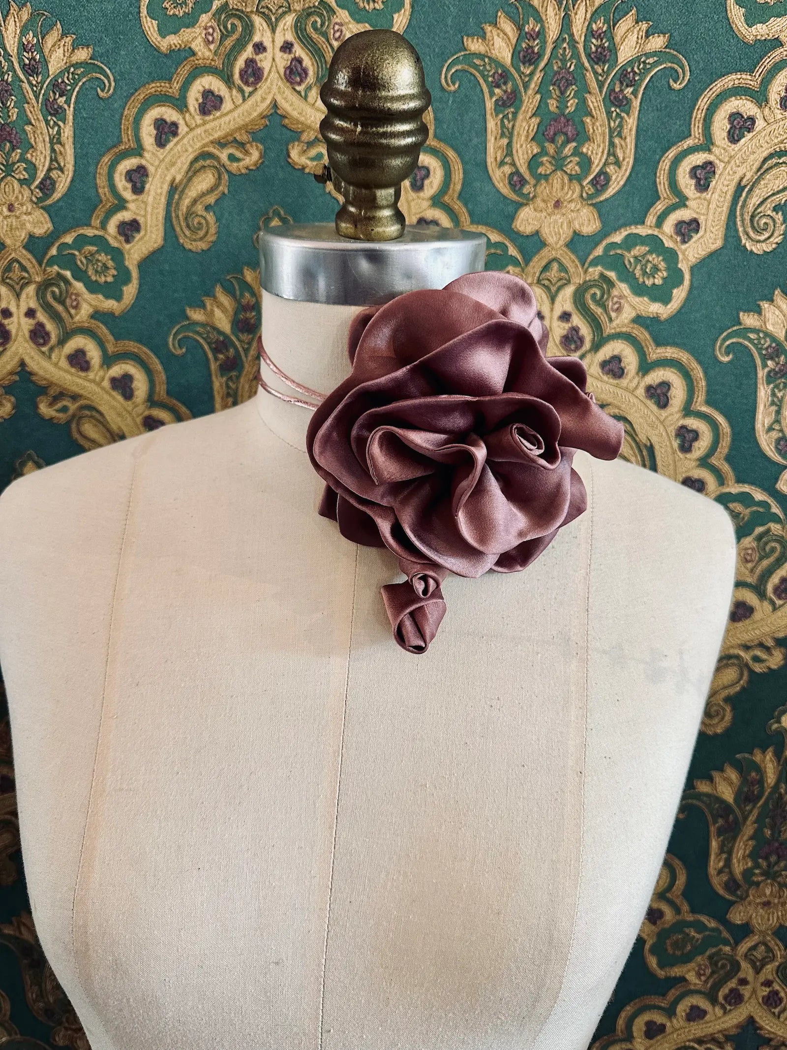 Broochella Rosetta blush pink handmade silk satin flower brooch and choker  Pictured on a mannequin. The background is green and gold damask wallpaper