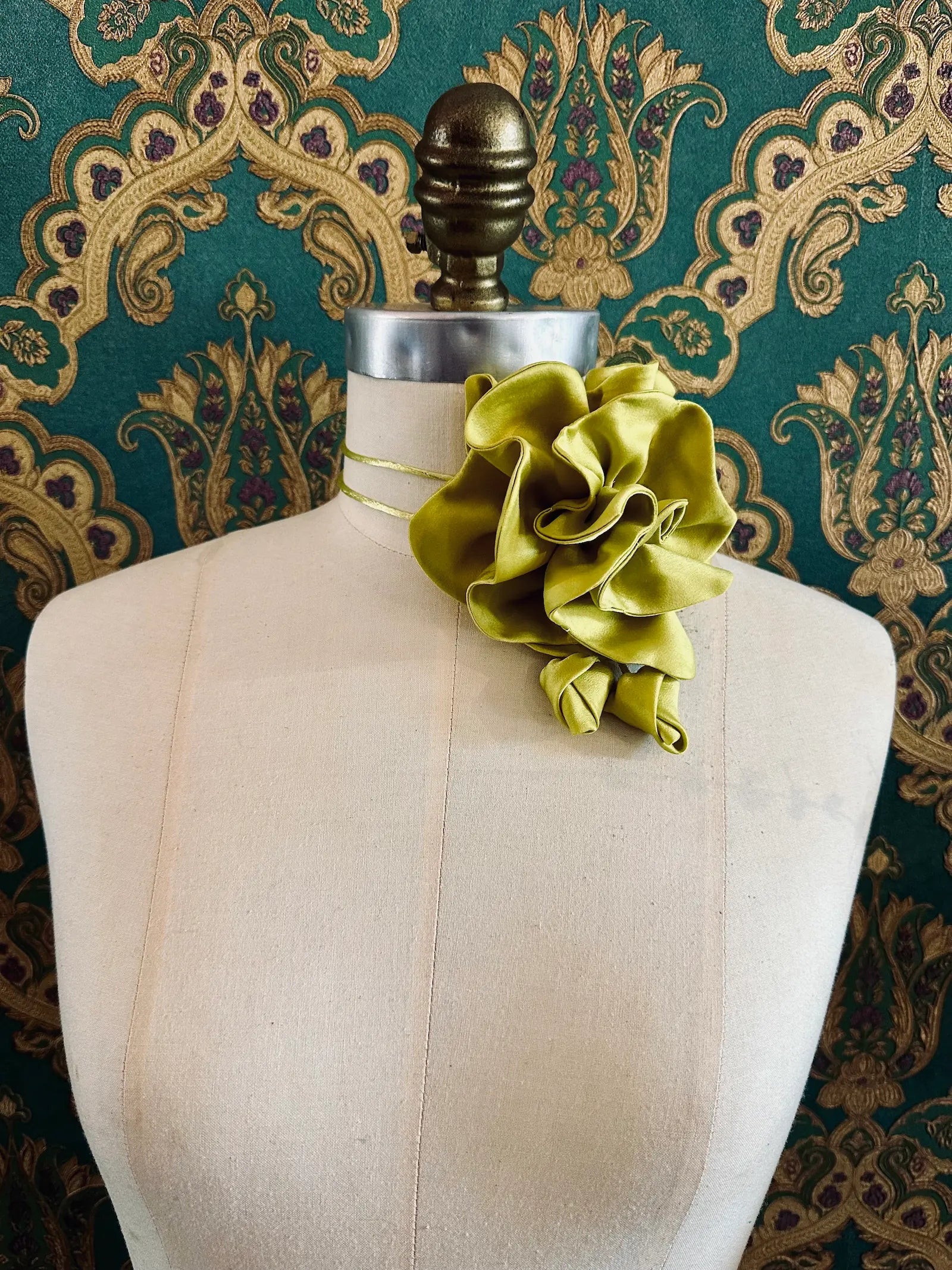 Broochella Rosetta chartreuse handmade silk satin flower brooch and choker  Pictured on a mannequin. The background is green and gold damask wallpaper