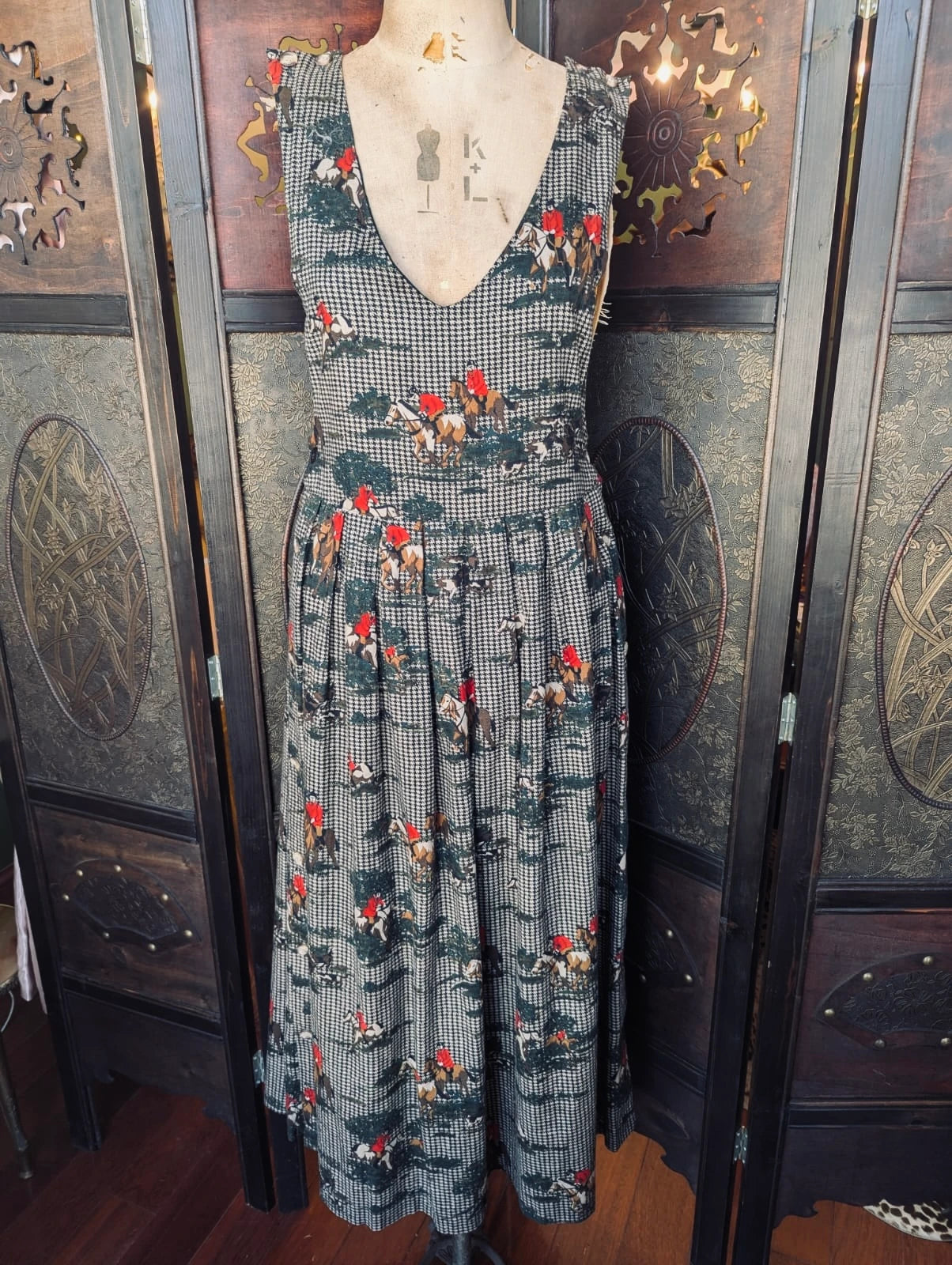 Broochella Vintage Charter Club by Jane houndstooth and equestrian print midi pinafore dress. It is presented on a vintage mannequin. The background is an ornate dark wood room divider. 