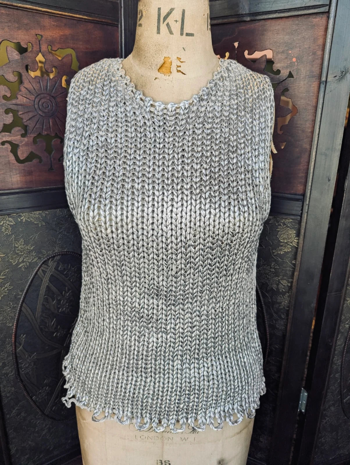 Broochella Zara Metallic silver knitted Textured sleeveless vest  top on a mannequin against a decorative wall.