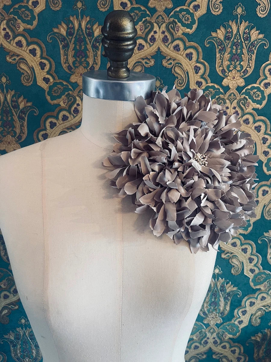 Broochella Crisanntemo large handmade designer beige fabric flower brooch. Pictured on a mannequin. The background is green and gold damask wallpaper.